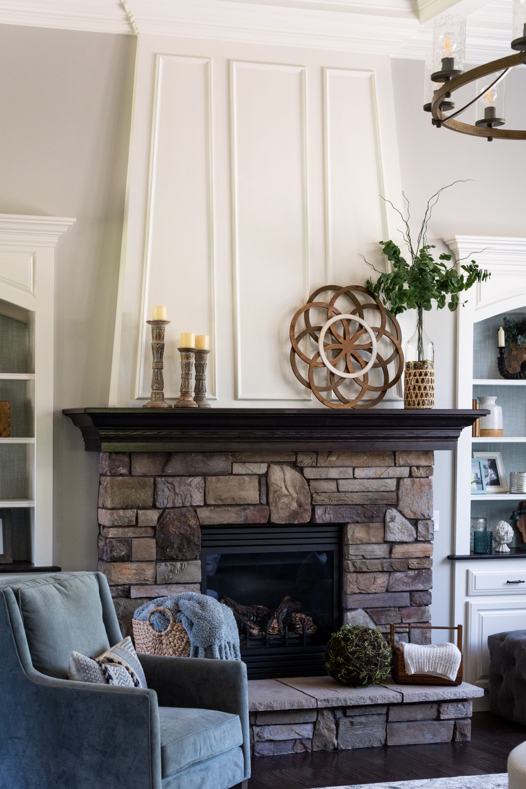 Living room stone fireplace and hearth with pillar candles and textured white molding to the ceiling