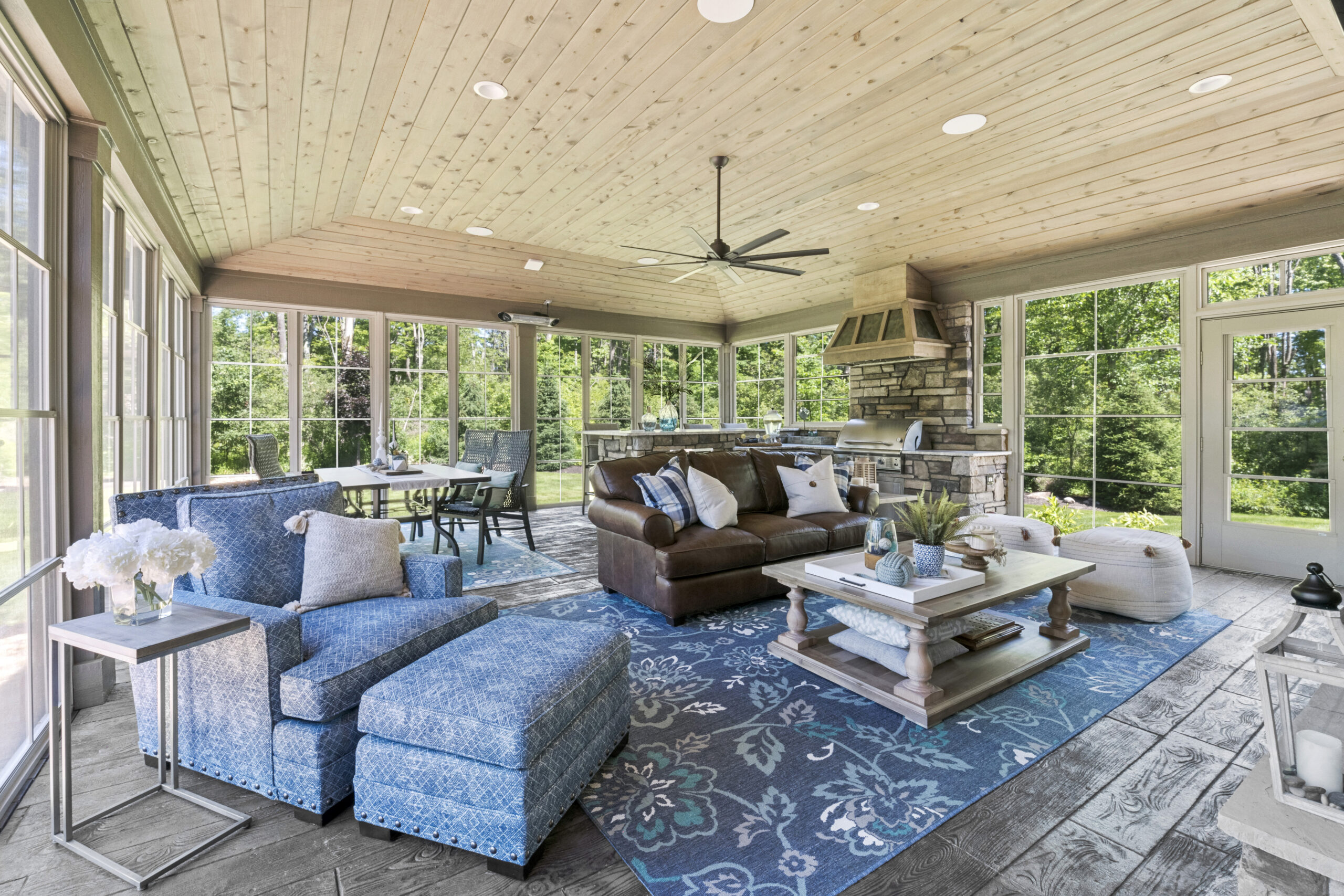 Sun room with grill area, dark leather couch, and light blue rug
