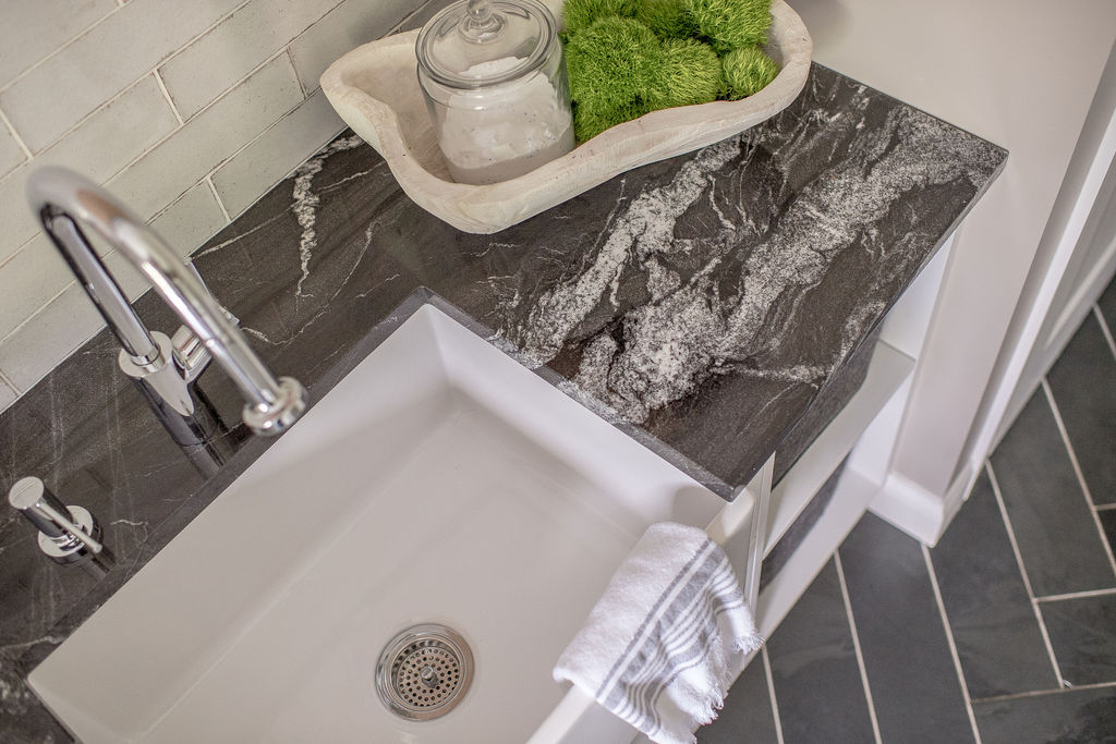 Laundry room sink with dark countertop and nickel hardware