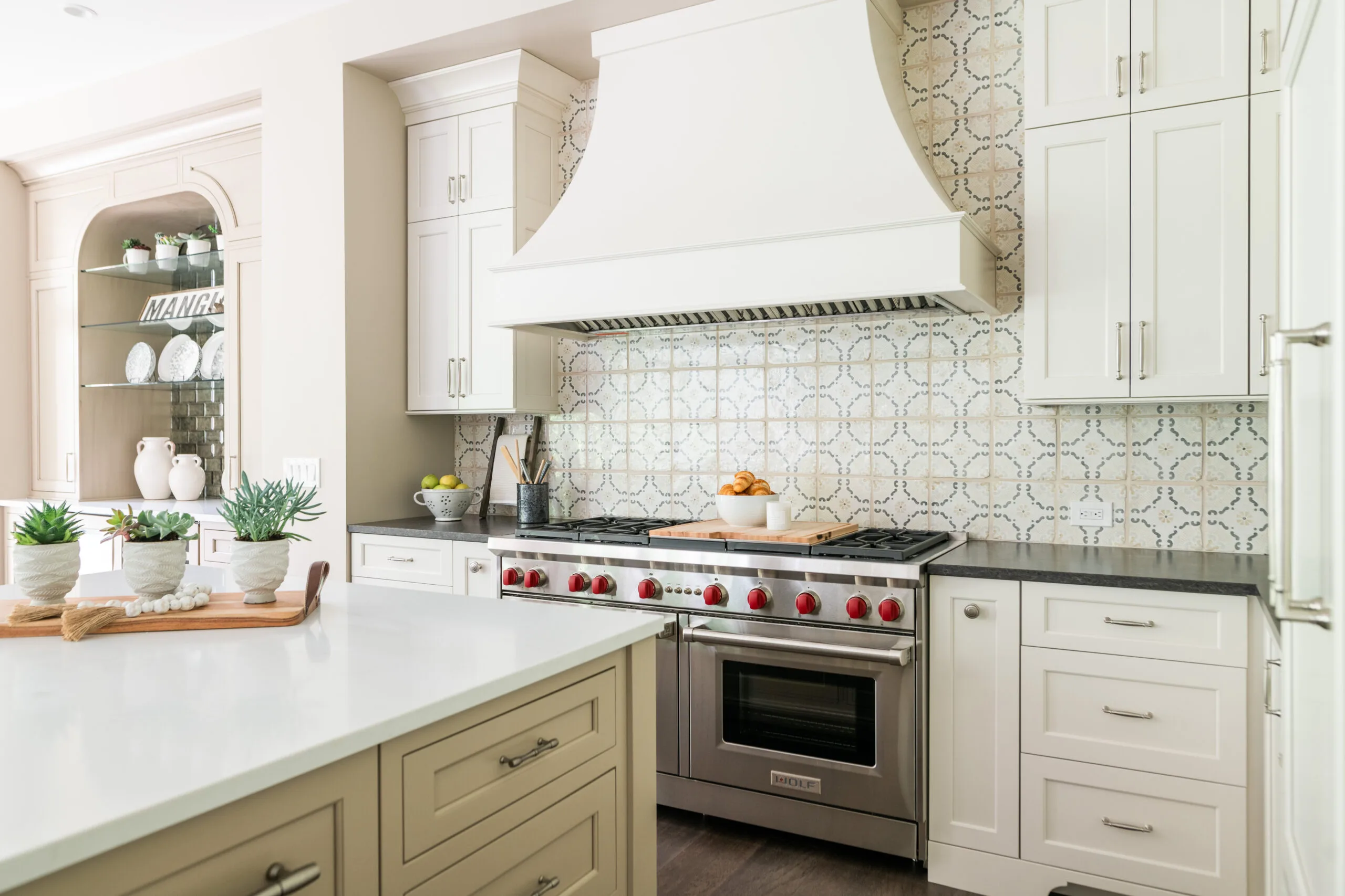 Luxury Kitchen with painted cabinetry and decorative painted hood with custom handmade pattered tiles with dark countertop