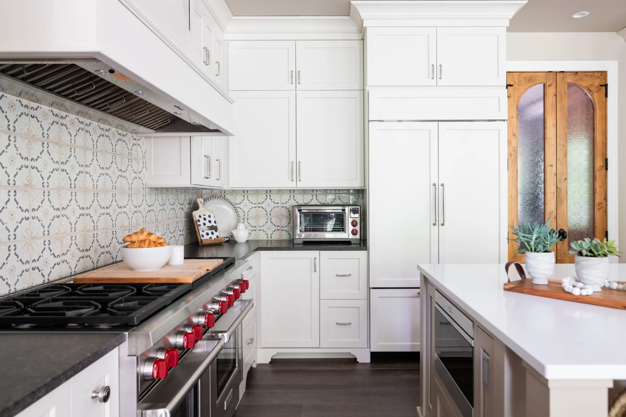 Luxury Kitchen with painted cabinetry and decorative painted hood with custom handmade pattered tiles with dark countertop