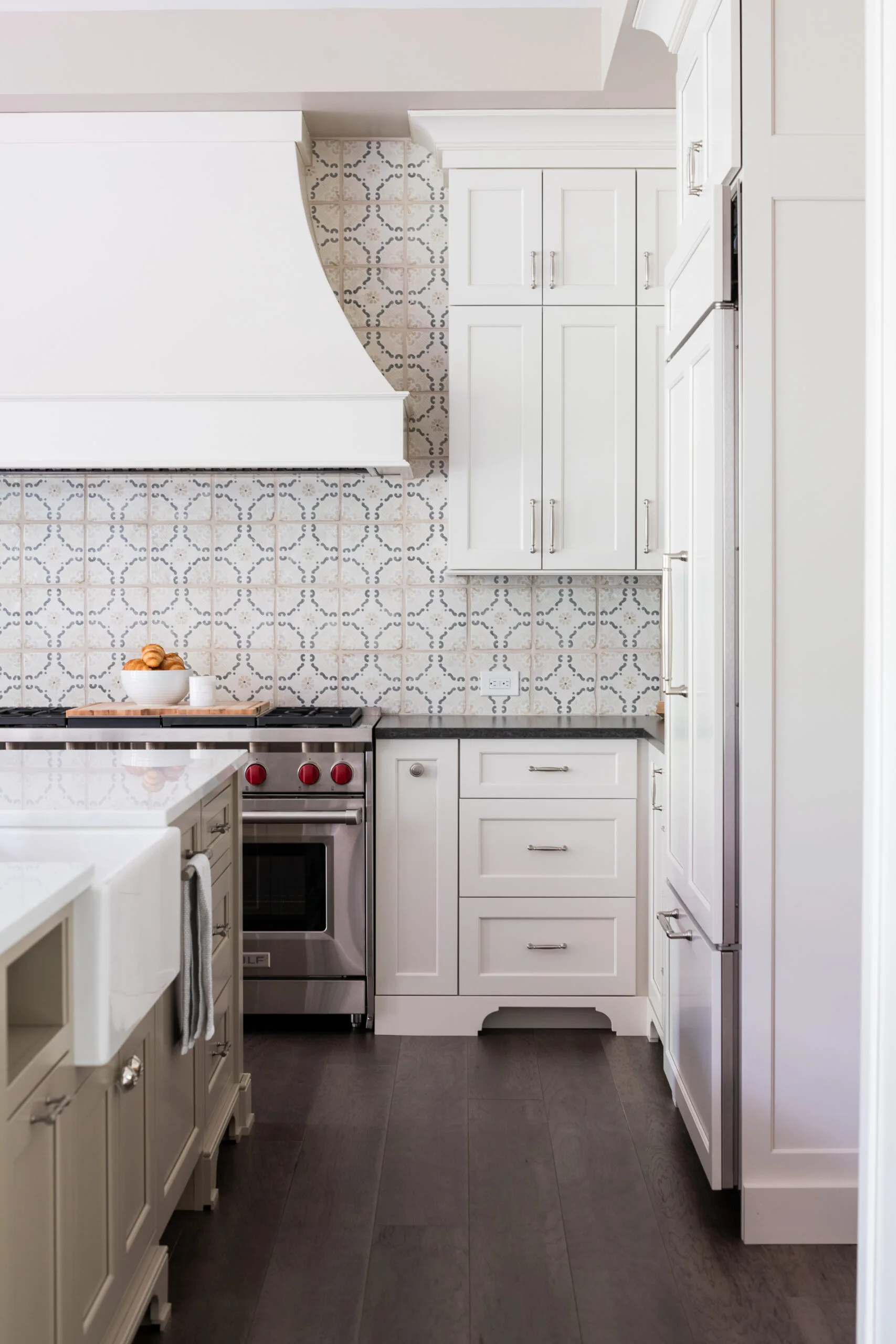 Luxury Kitchen with painted cabinetry and decorative painted hood with custom handmade pattered tiles with dark countertop