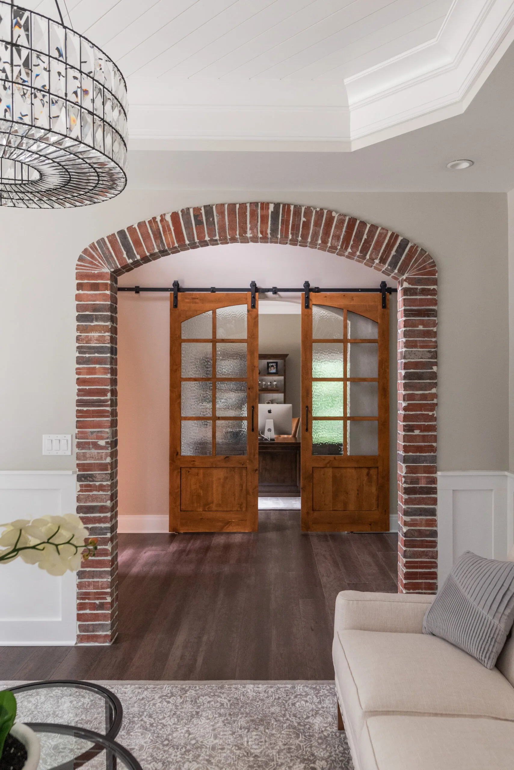 Luxury Sitting Room with tray ceiling and view to foyer and office. Brick cased arch brick opening in sitting room and custom sliding doors on office