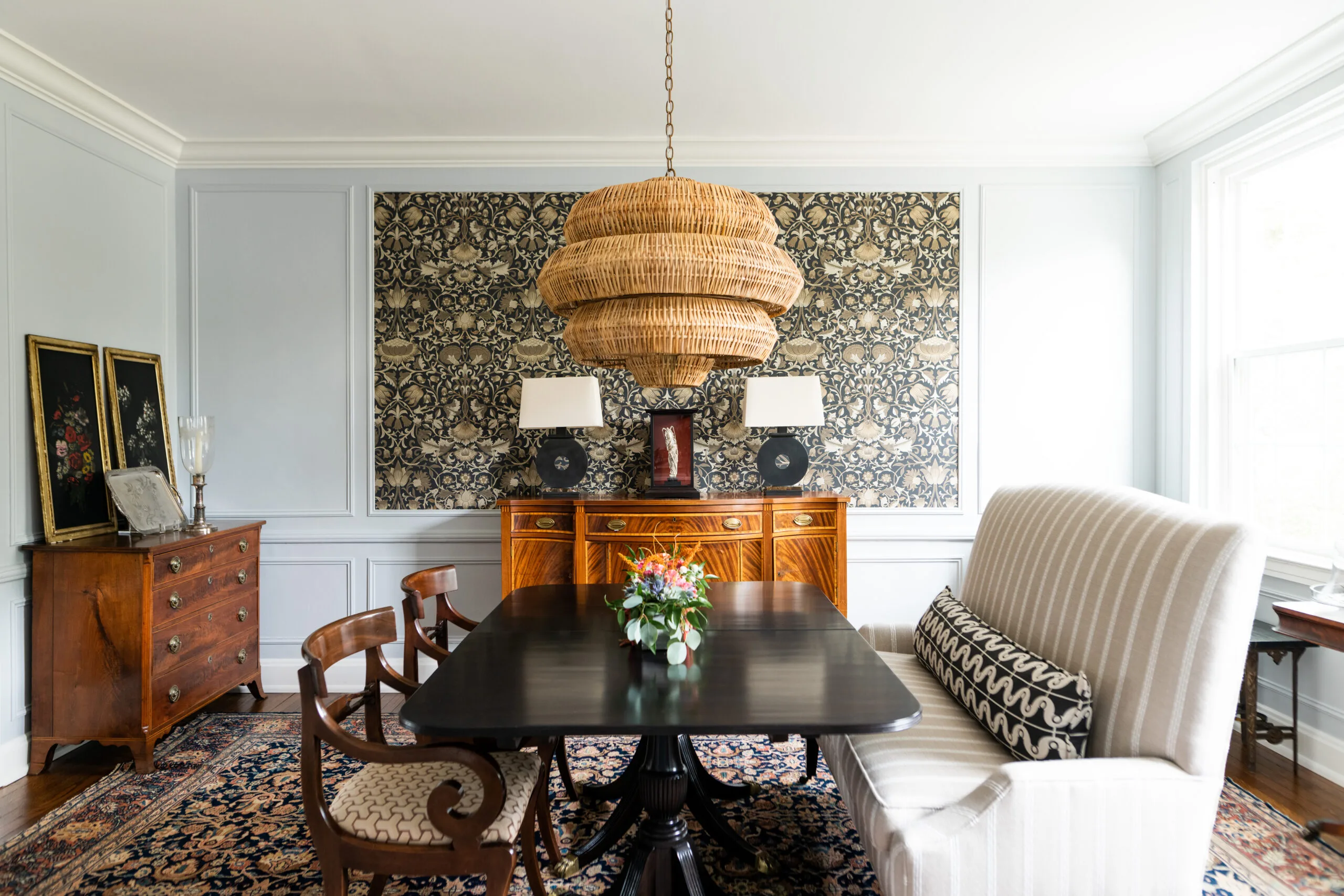 dinning room with large upholstered banquette, rattan woven shade candelier and traditional polished dining table
