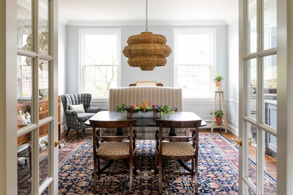 dinning room with large upholstered banquette, rattan woven shade candelier and traditional polished dining table