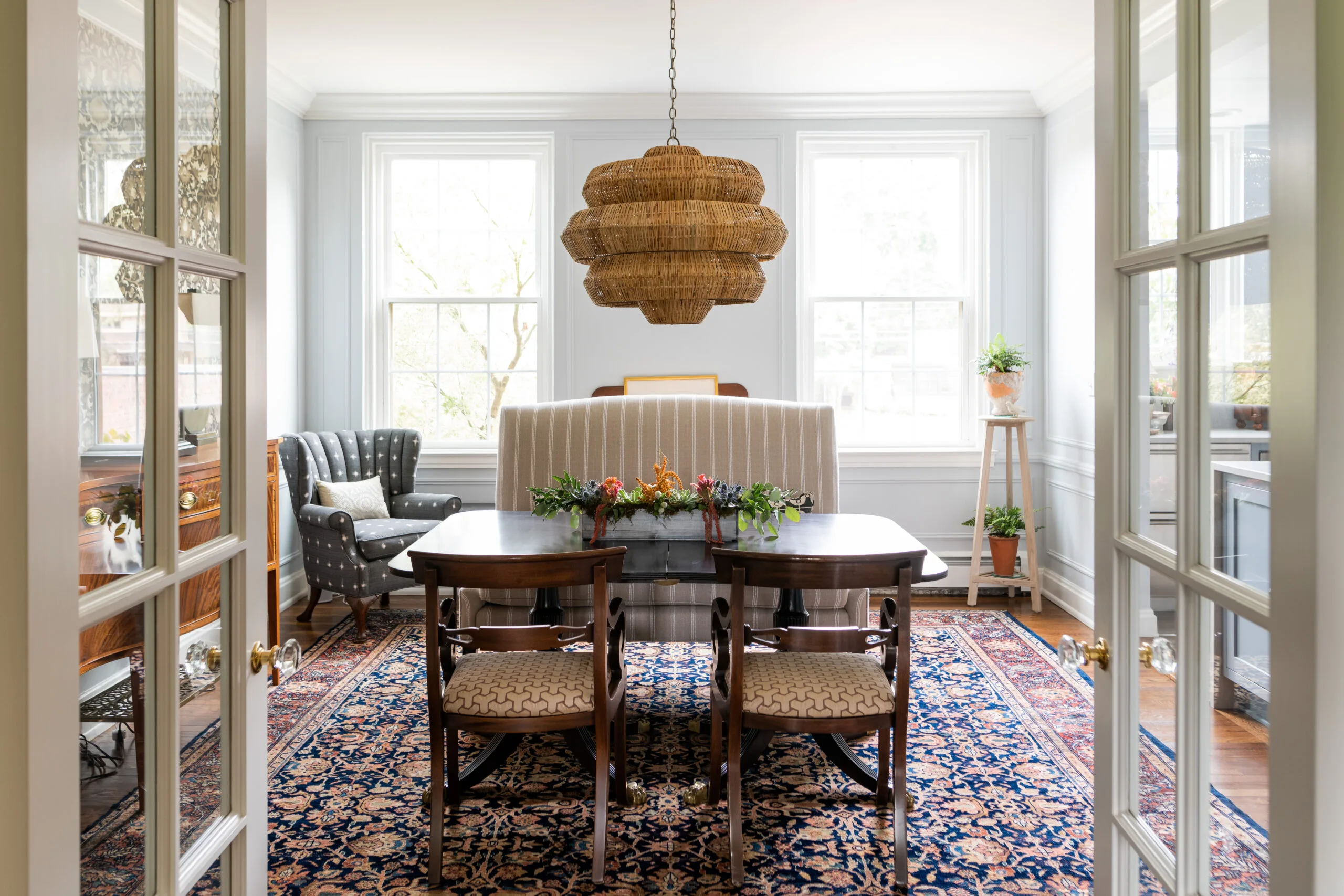 dinning room with large upholstered banquette, rattan woven shade candelier and traditional polished dining table