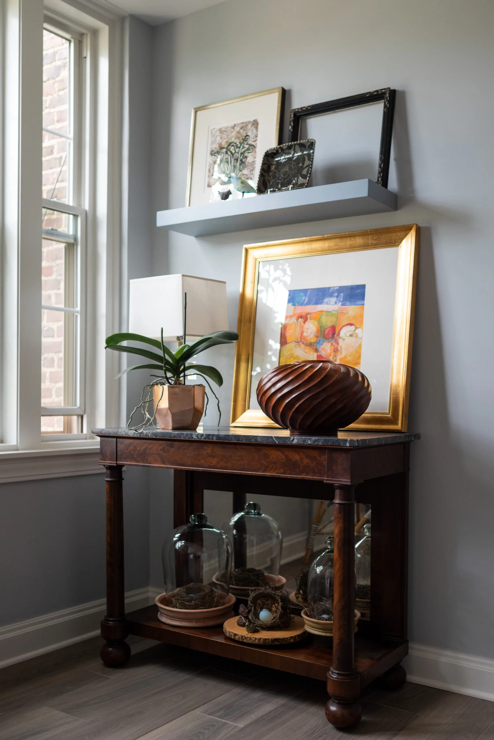antique console table in kitchen with curated art and floating shelf
