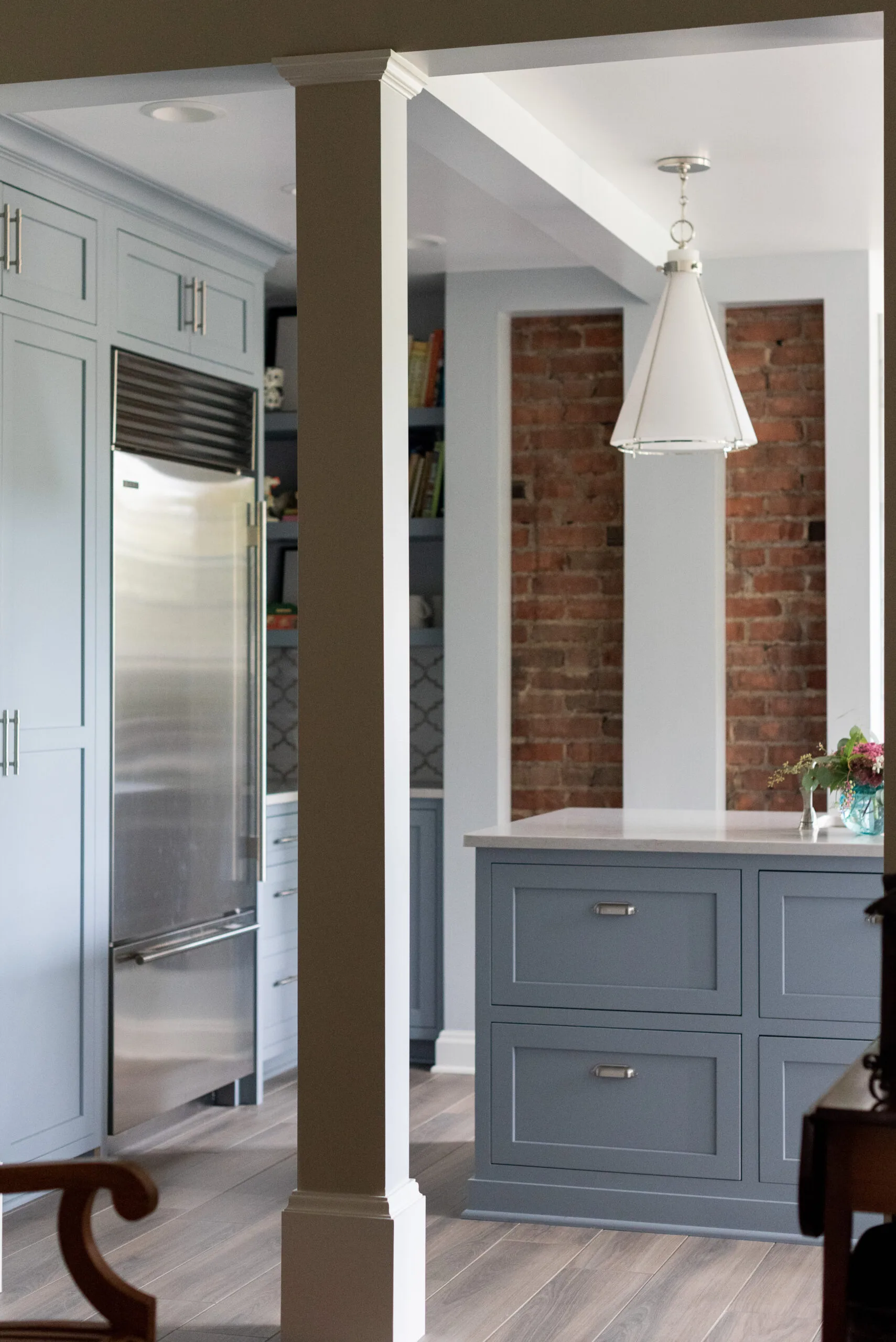 luxury kitchen appliances and painted cabinetry with exposed brick design and modern pendant light