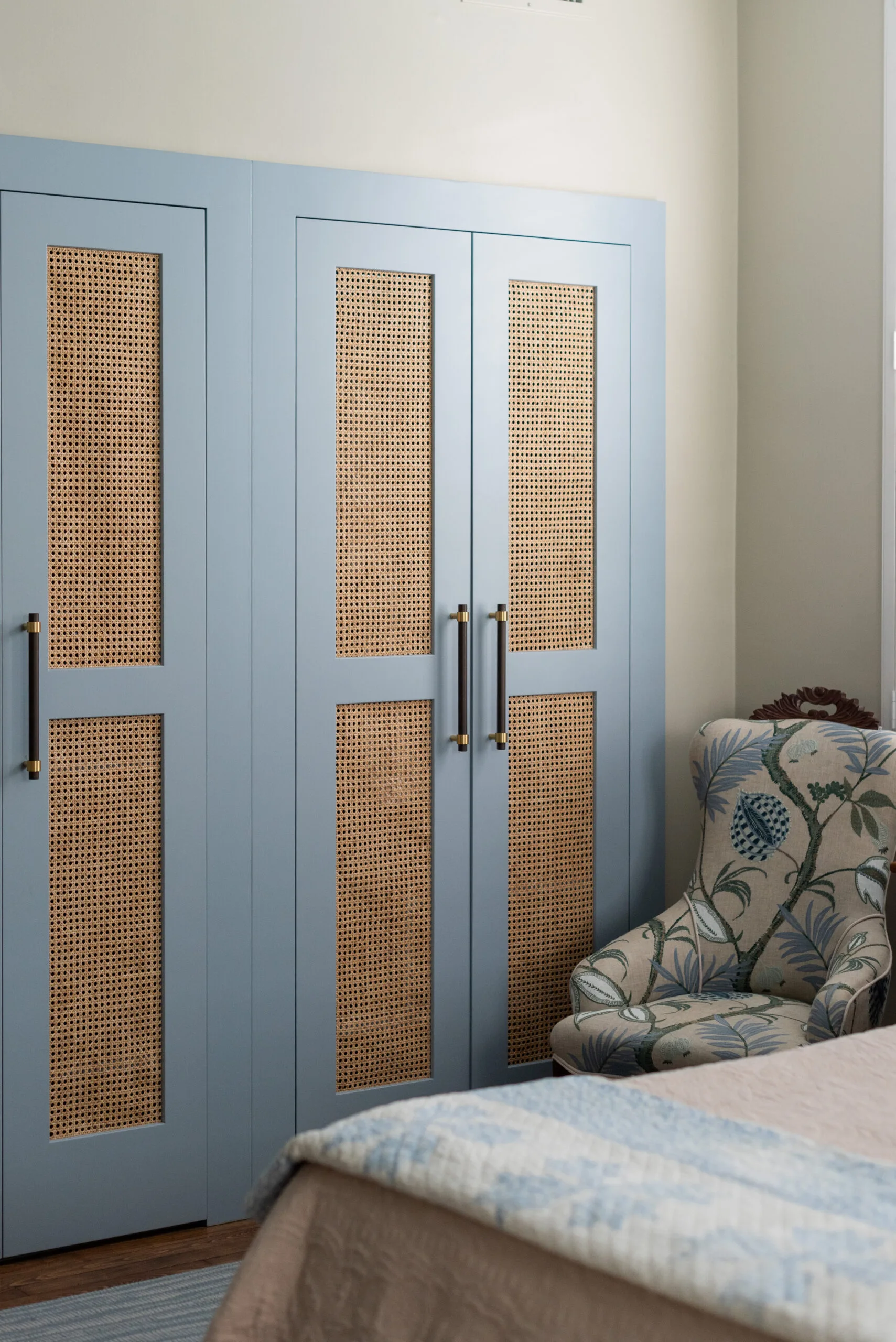 primary bedroom custom closet built ins painted in blue with rattan door insert