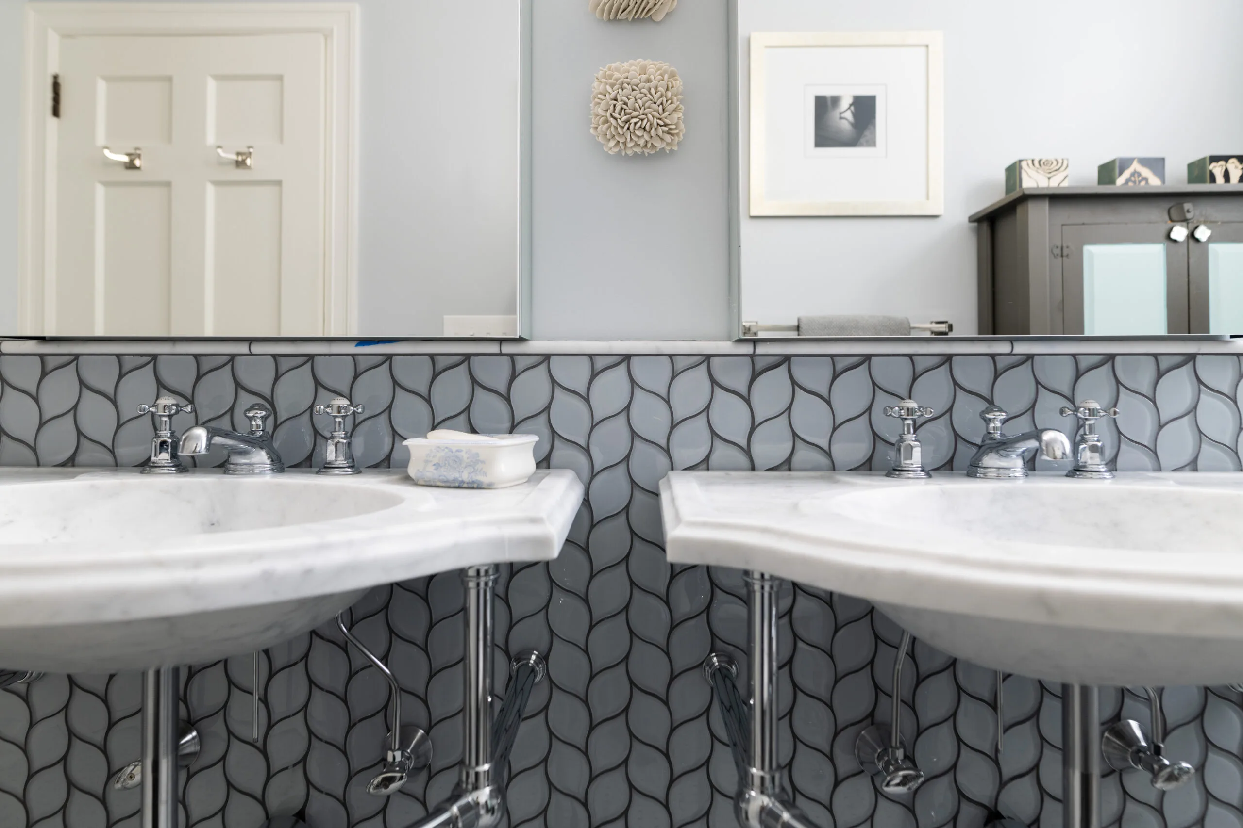 classic primary bathroom with chrome pedestal sinks and mosaic backsplash with purfume ledge and medicine cabinets