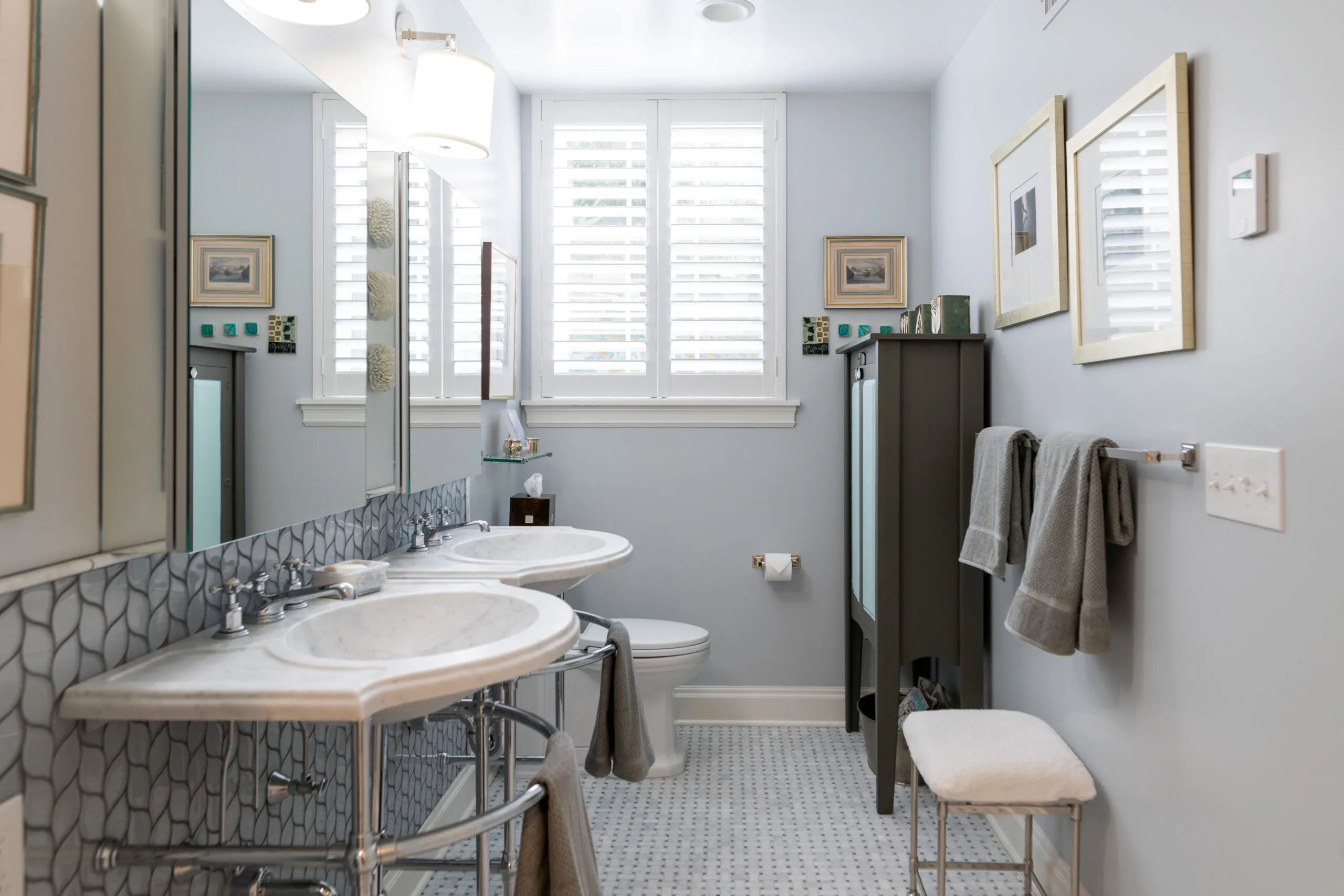 classic primary bathroom with chrome pedestal sinks and mosaic basketweave marble floor