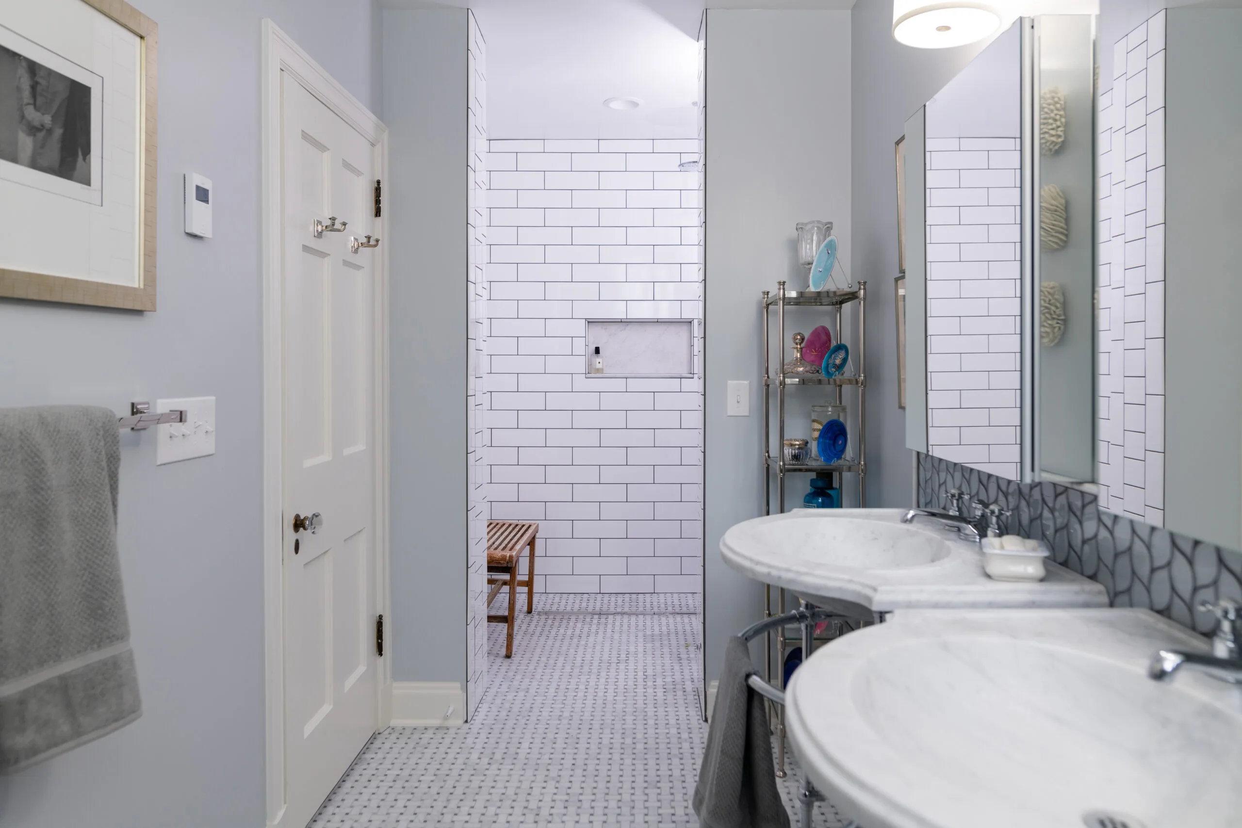 classic primary bathroom with chrome pedestal sinks and mosaic basketweave marble floor