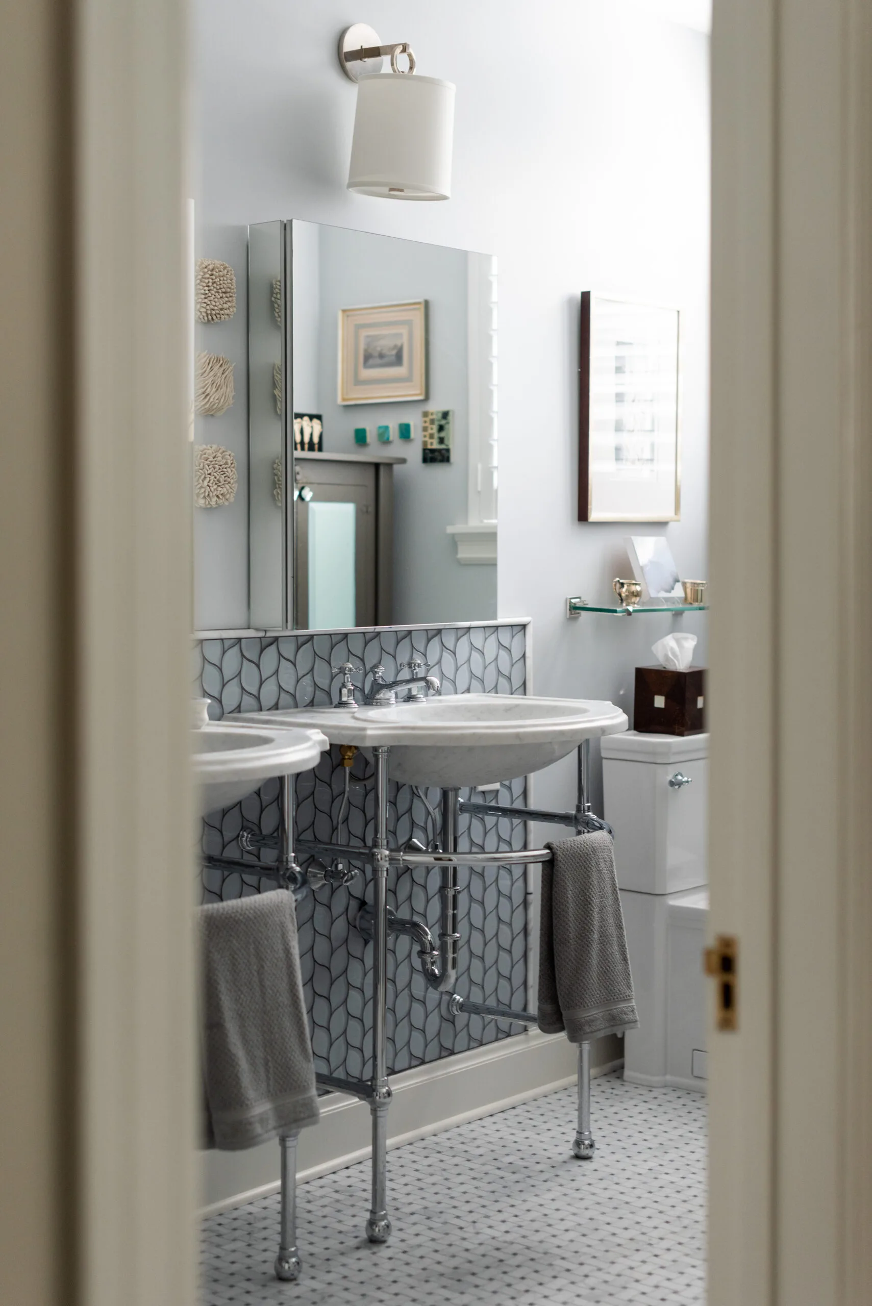 classic primary bathroom with chrome pedestal sinks and mosaic basketweave marble floor