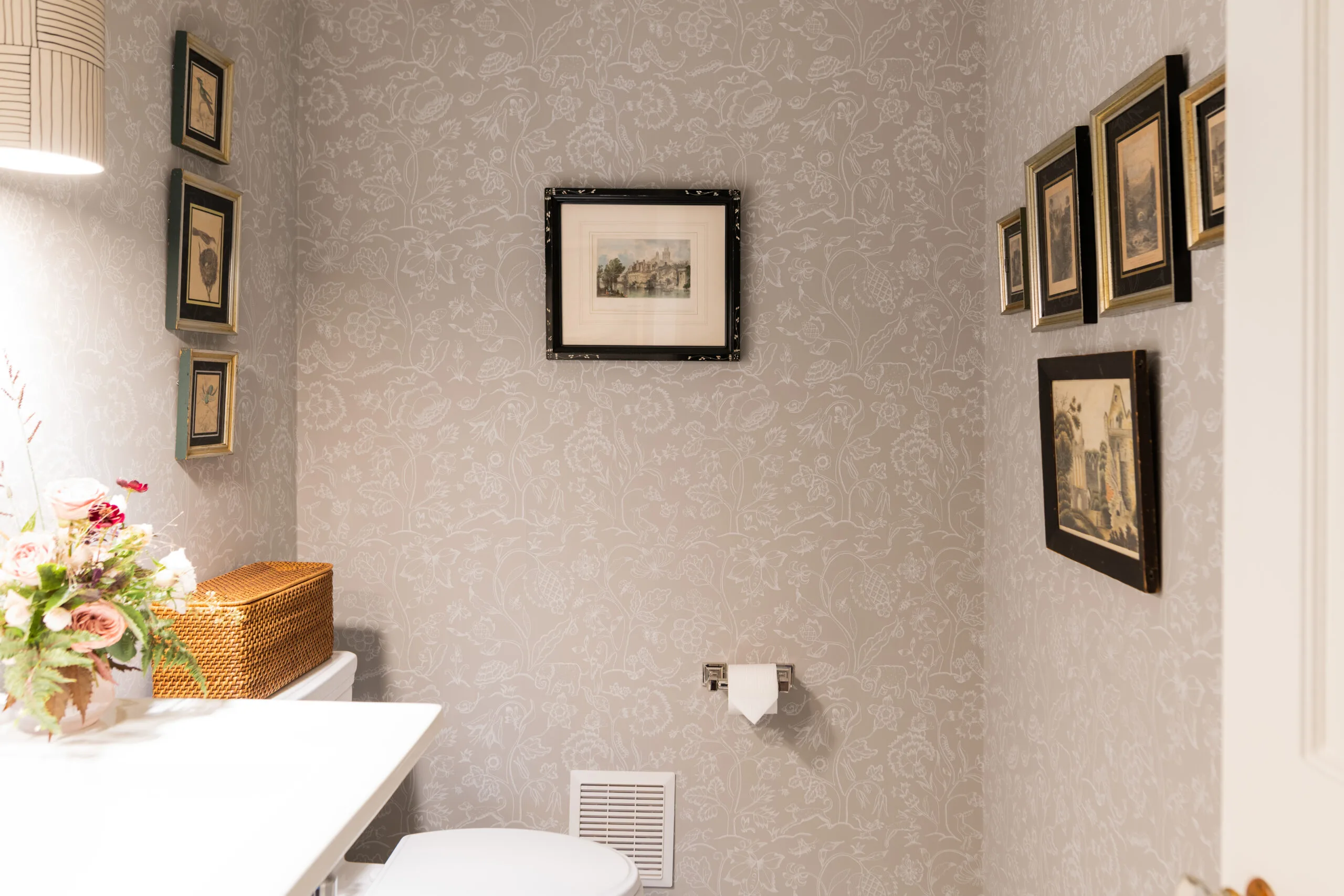 powder room with tone on tone simple floral wallpaper and antique artwork