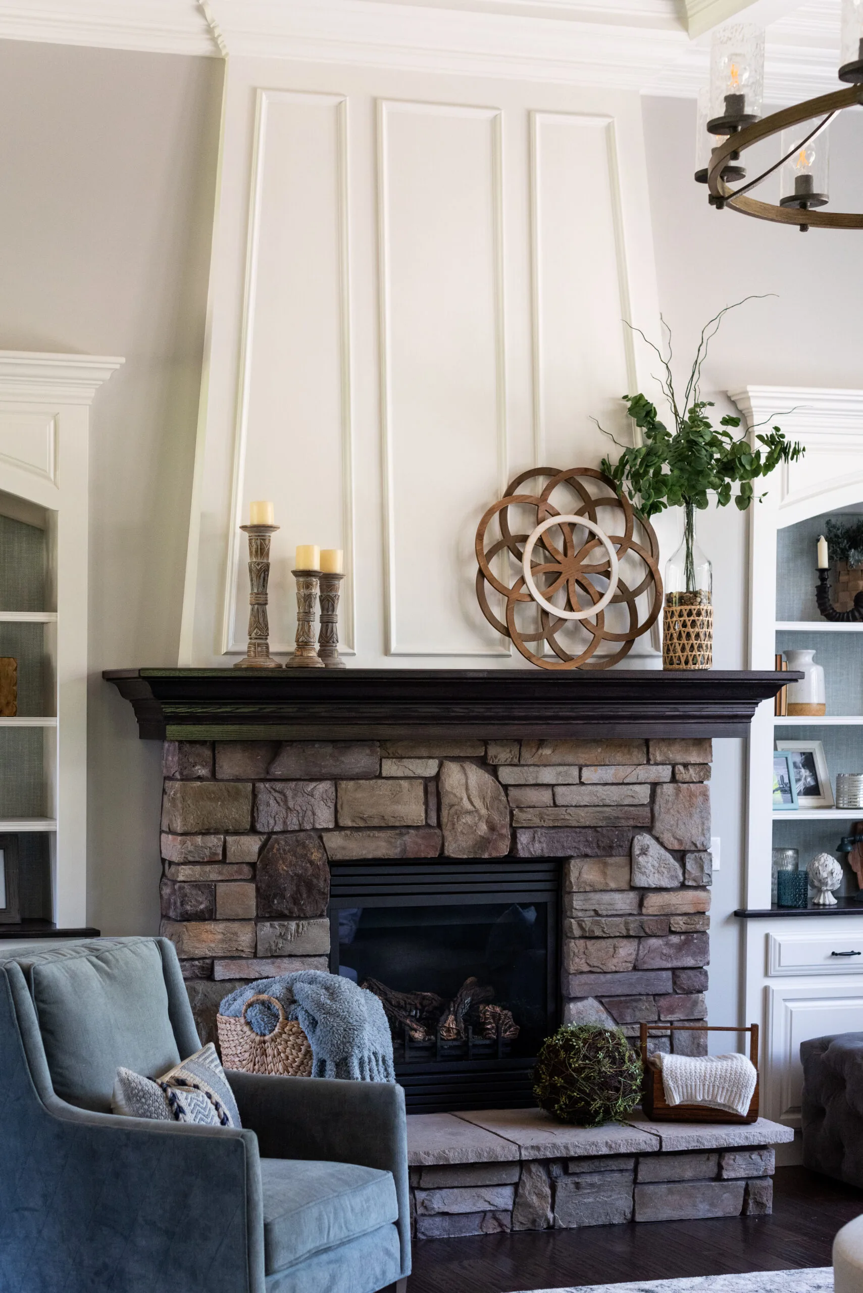 Living room stone fireplace and hearth with pillar candles and textured white molding to the ceiling