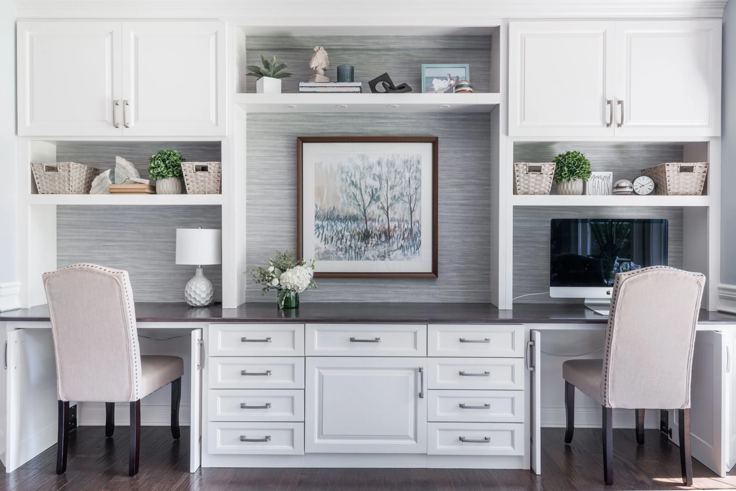 Home office with built-in white cabinetry and two desk areas with upholstered chairs