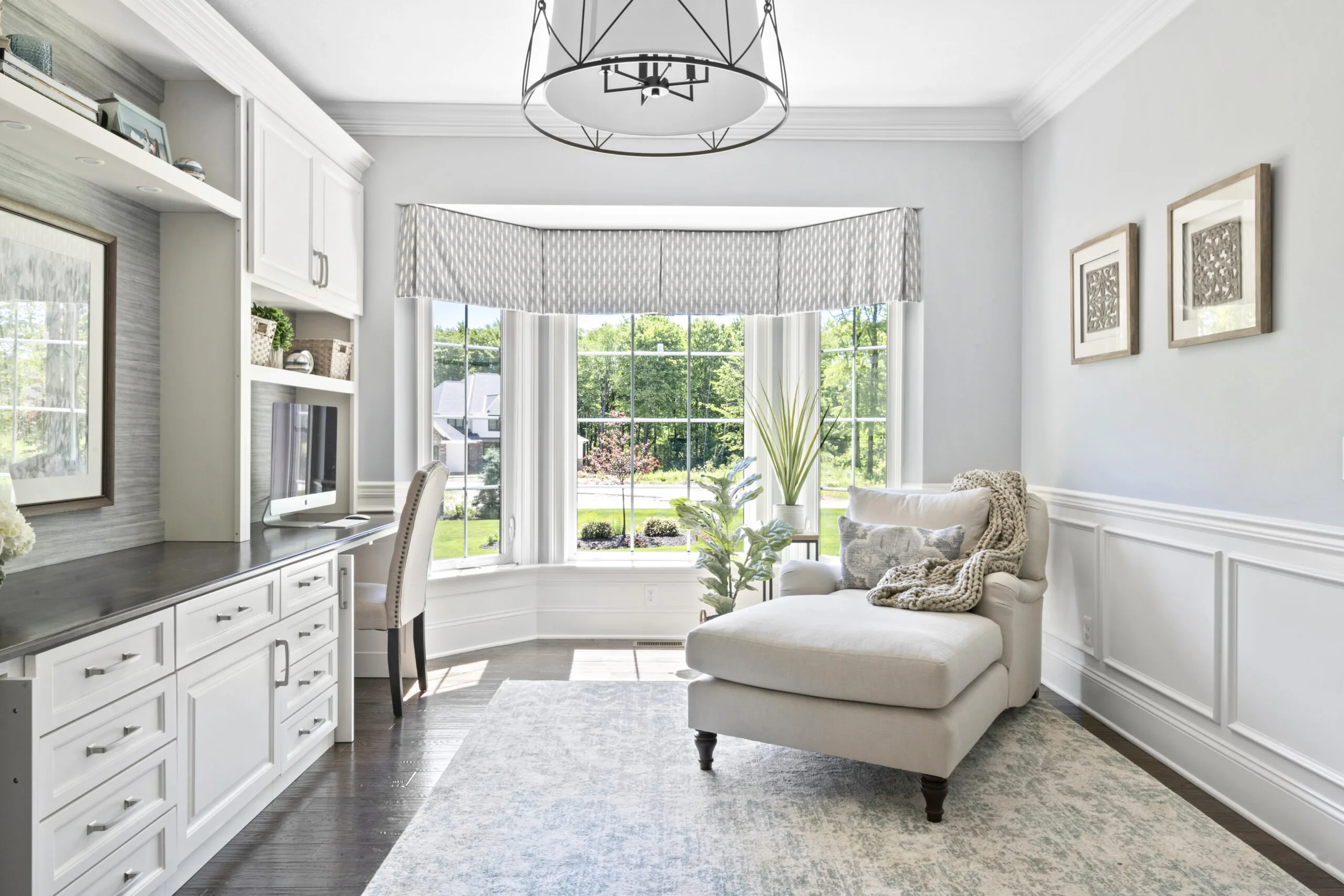 Home office with a bay window and cream colored chaise lounge in corner