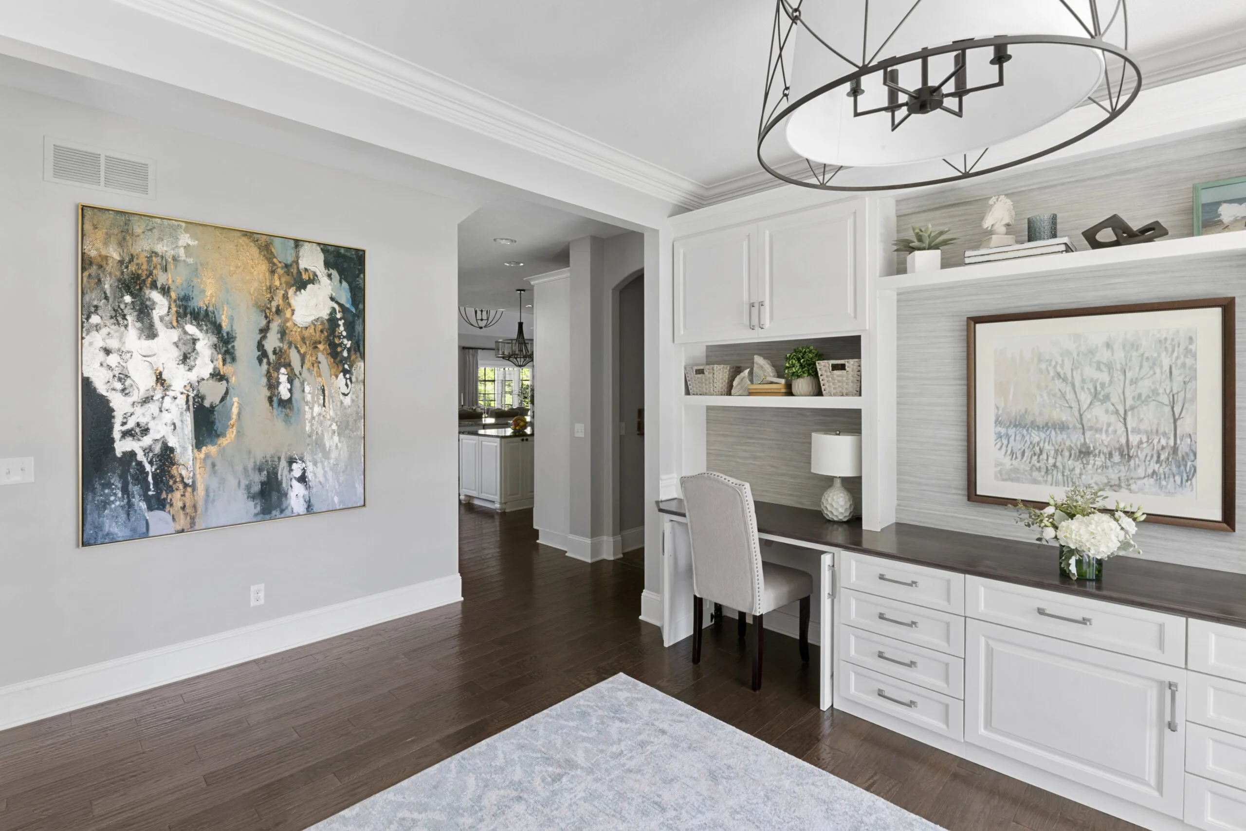 Home office with white cabinetry, abstract art, and tree art in blue and gold hues