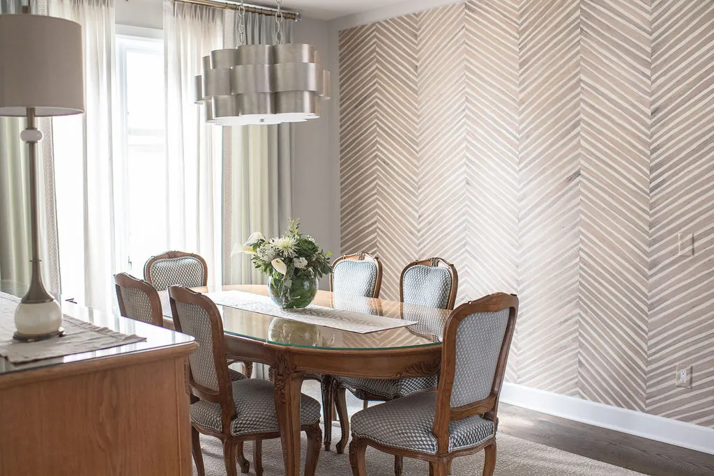 Dining room with a wooden table, upholstered, blue dining chairs, and neutral herringbone wallpaper