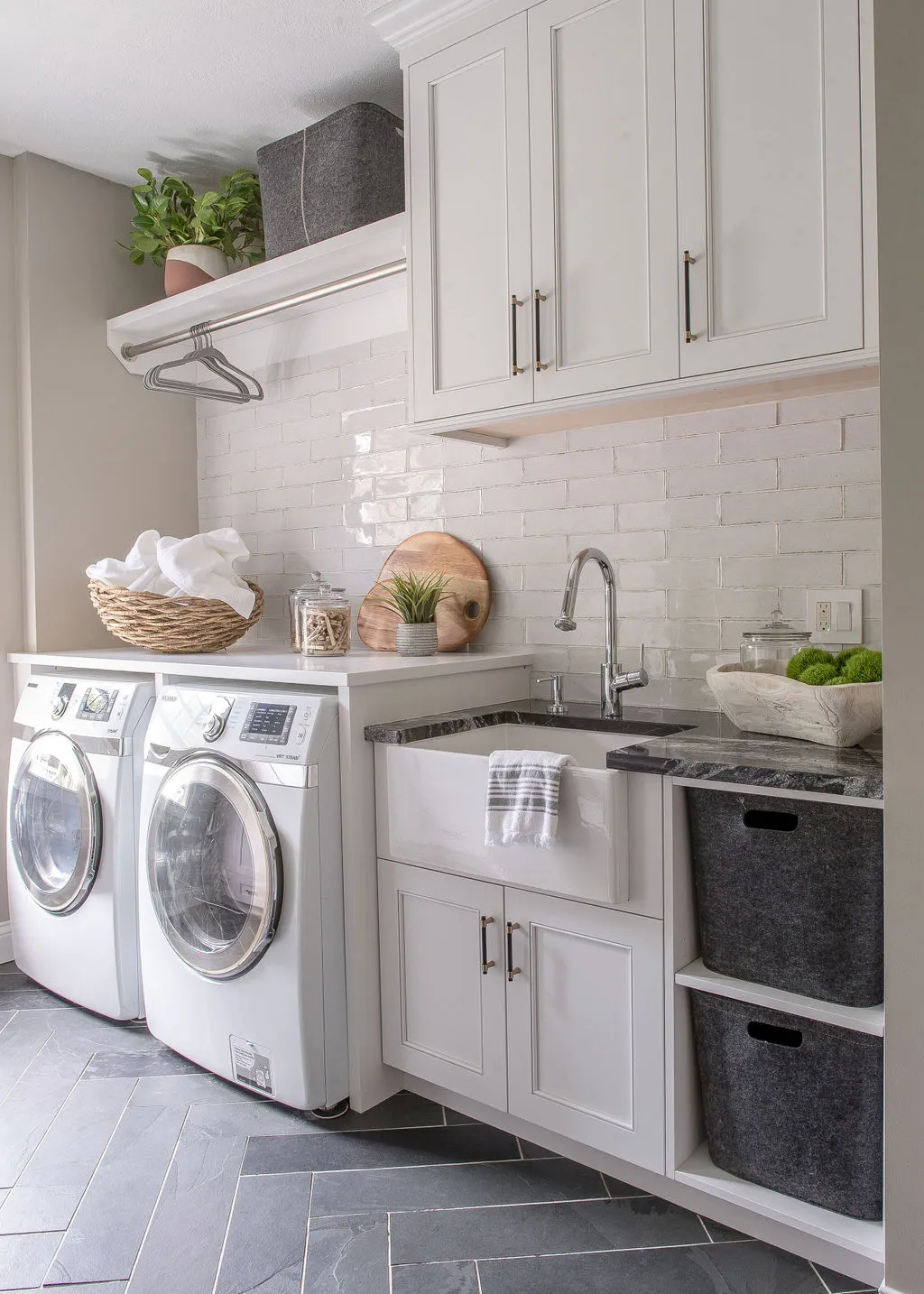 Laundry room with neutral subway tile backsplash, white cabinetry, and dark herringbone flooring