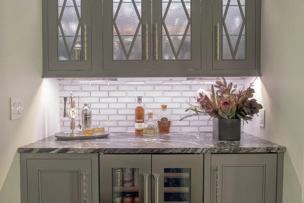 Moody bar space with neutral cabinetry with under cabinet lighting and dark countertops