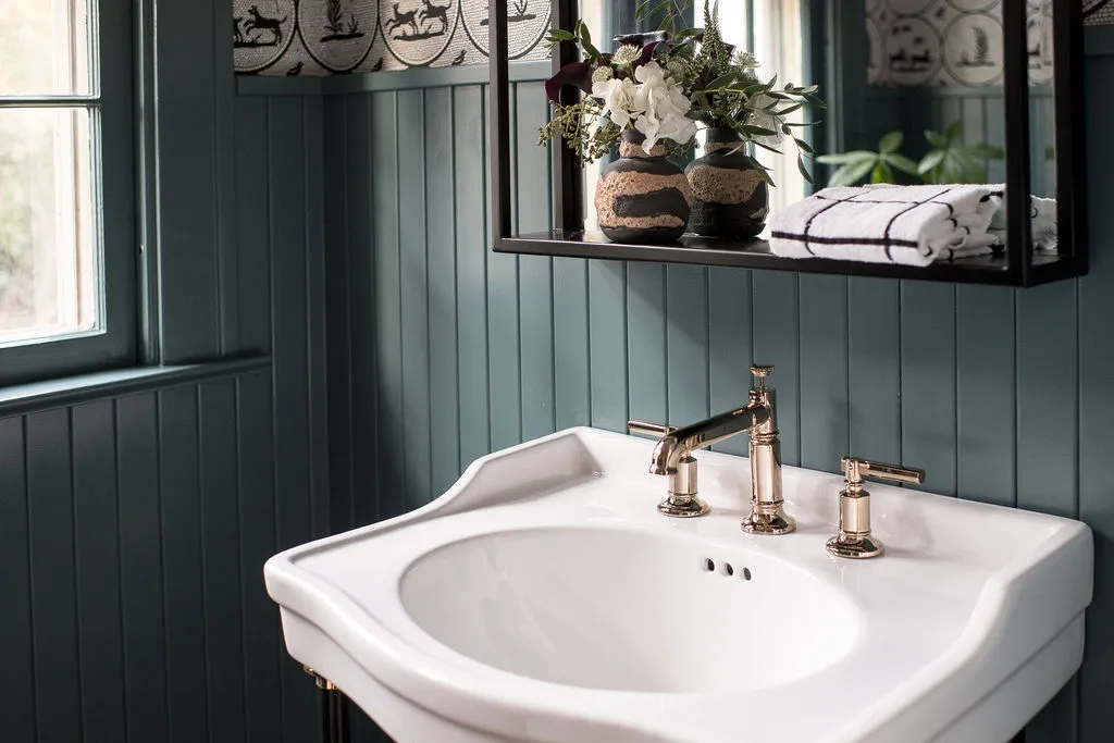 pedestal bathroom sink with deep green wall color for a moody guest bathroom