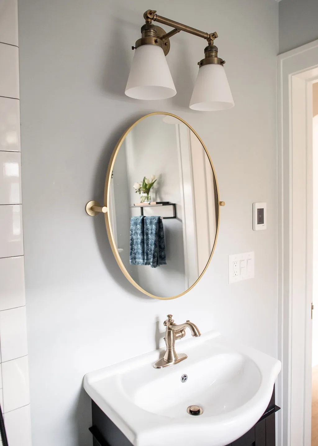 bathroom vanity with round mirror and golden light fixtures