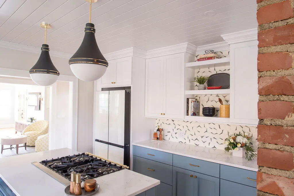 Renovated kitchen with blue cabinets, black pendant lights, and clean white tile