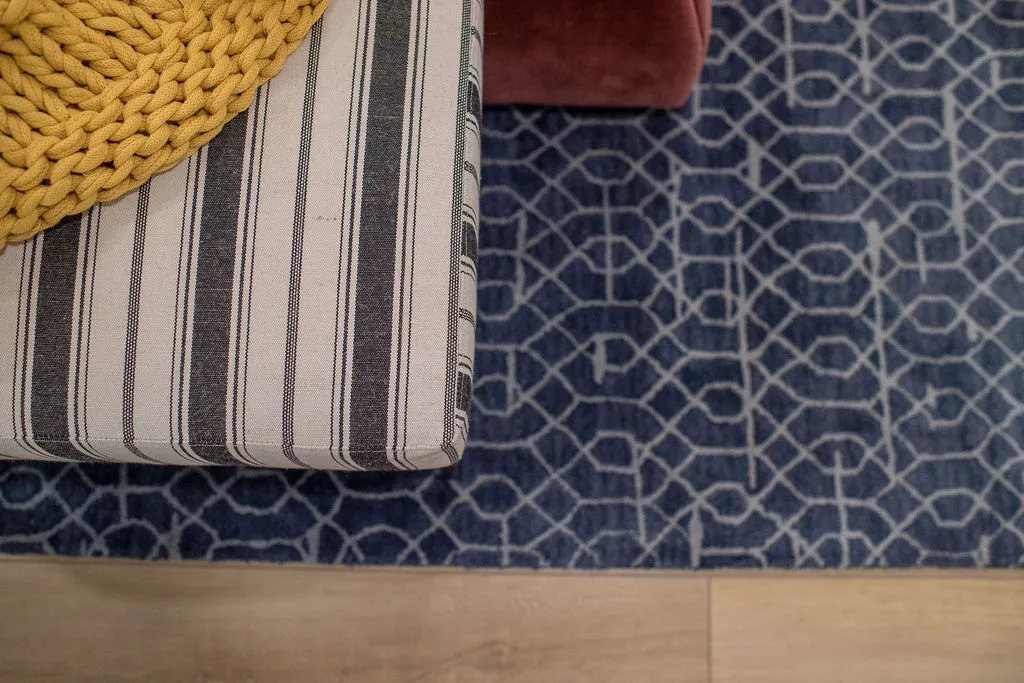 Image looking down on a striped bench over a blue pattern rug