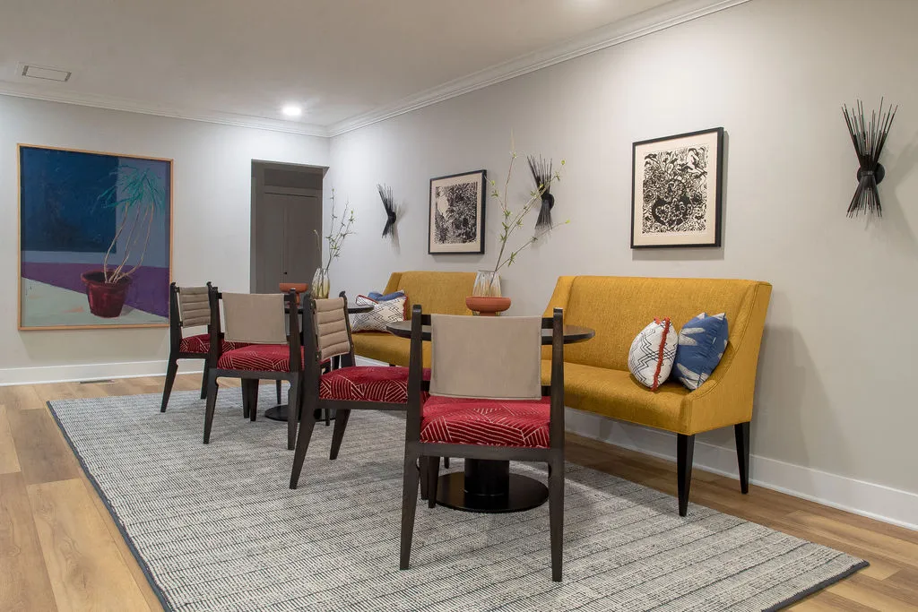 Seating area with yellow, upholstered benches, and red patterned dining chairs