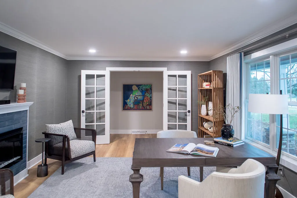 Office with a desk and chair, lounge chair, and bookcase with glass french doors to exit