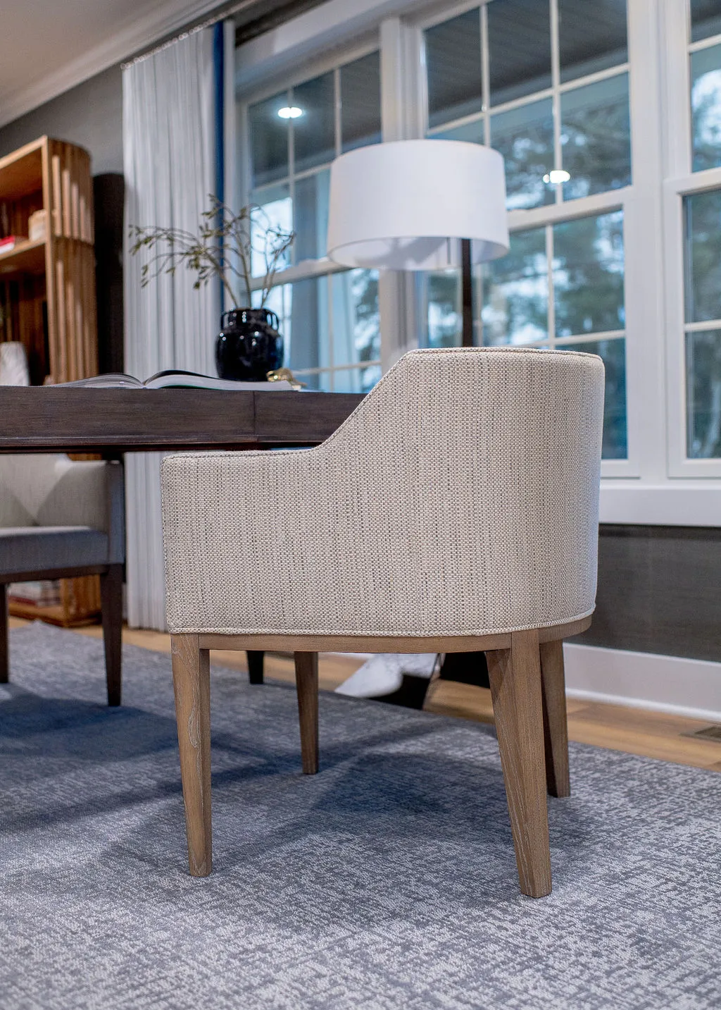 Close up image of an upholstered, neutral desk chair tucked underneath a wooden desk