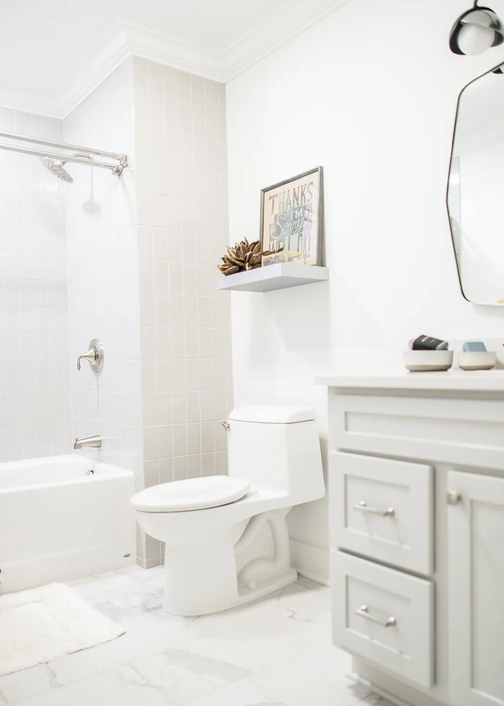 Light neutral and white bathroom with a small vanity, toilet, and shower