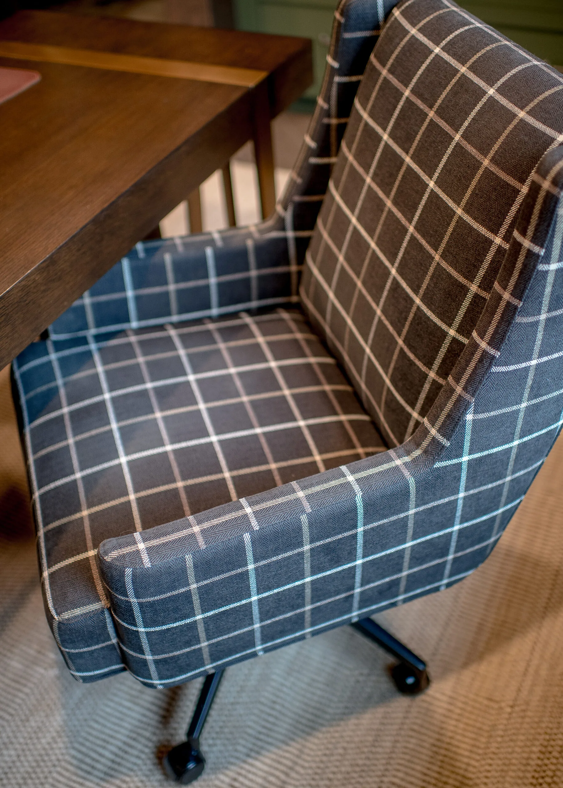 Image of an upholstered plaid desk chair tucked under a wooden desk