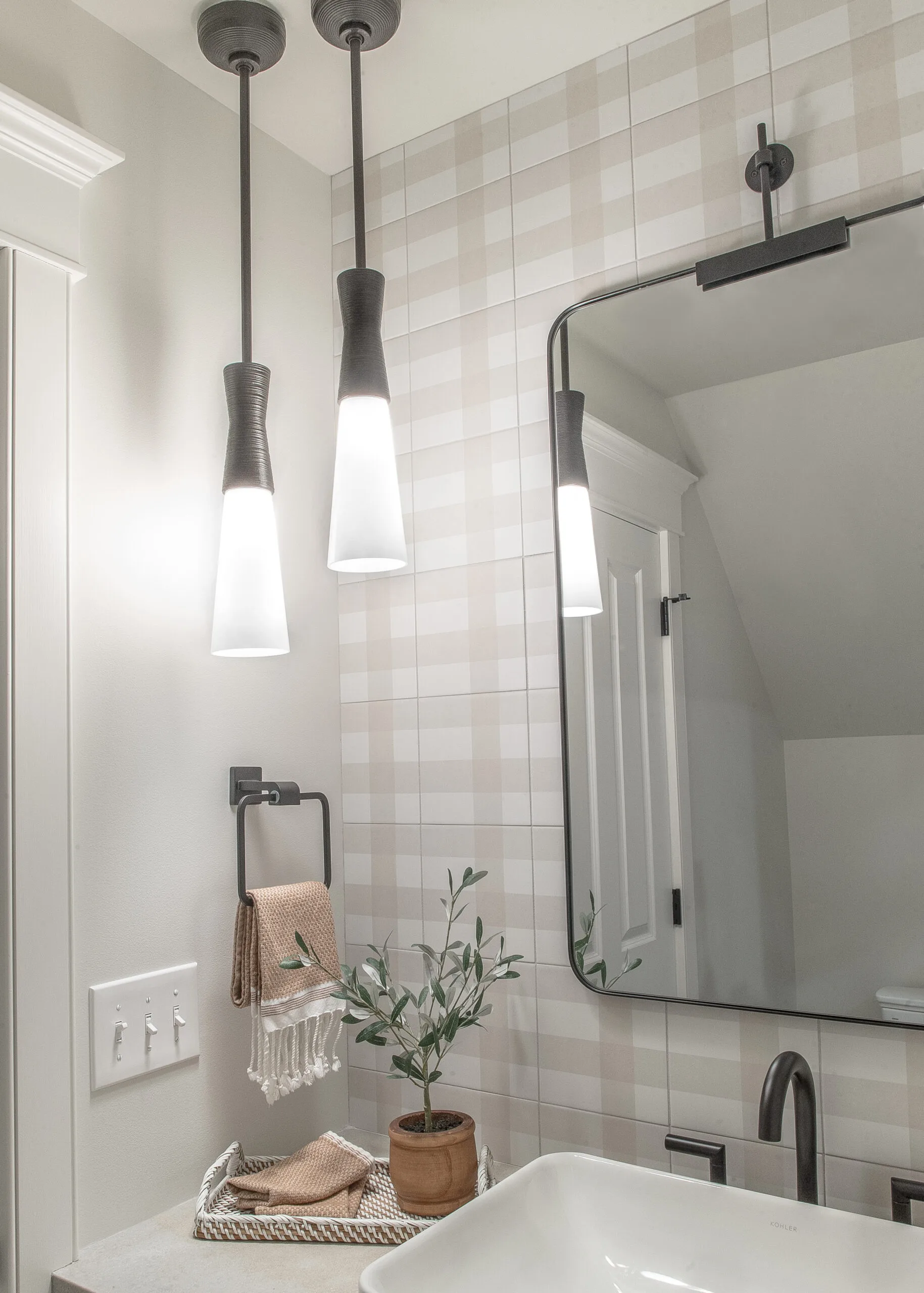 Close up on a bathroom mirror with a hanging pendant beside and greenery underneath