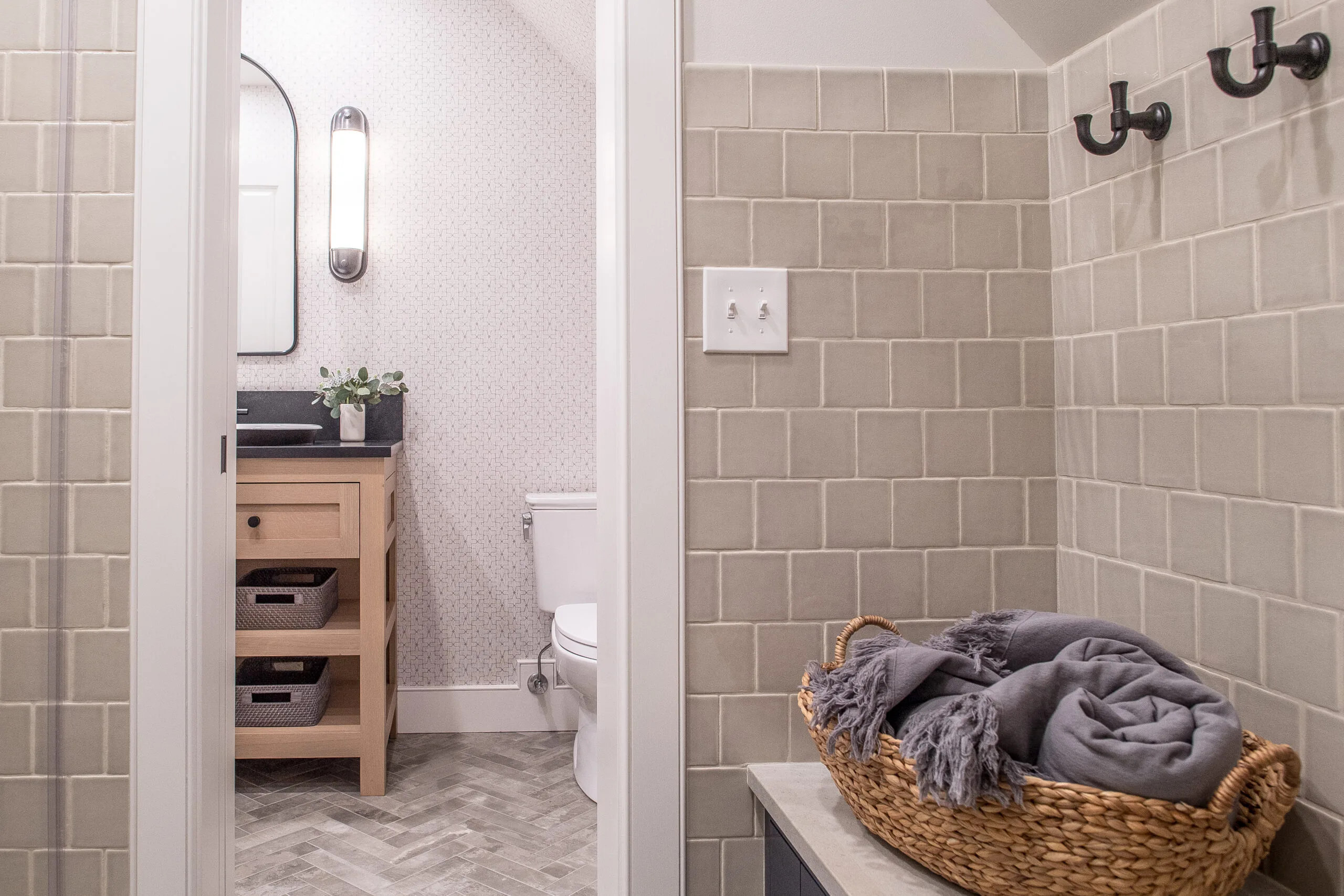 Entry of a bathroom with a bench, hooks, and light brown tile