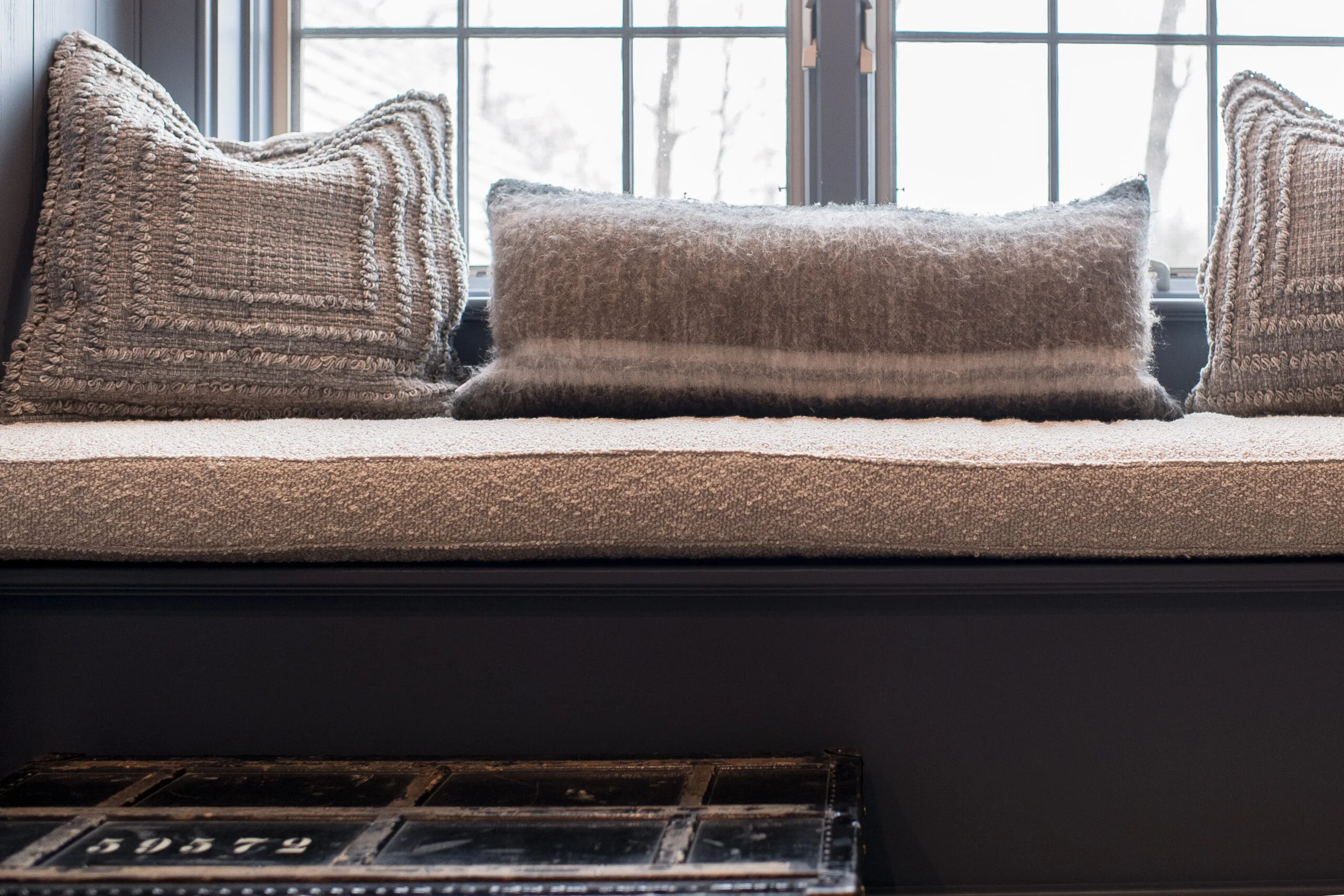 Close up image of a navy window seat with a neutral cushion and pillows