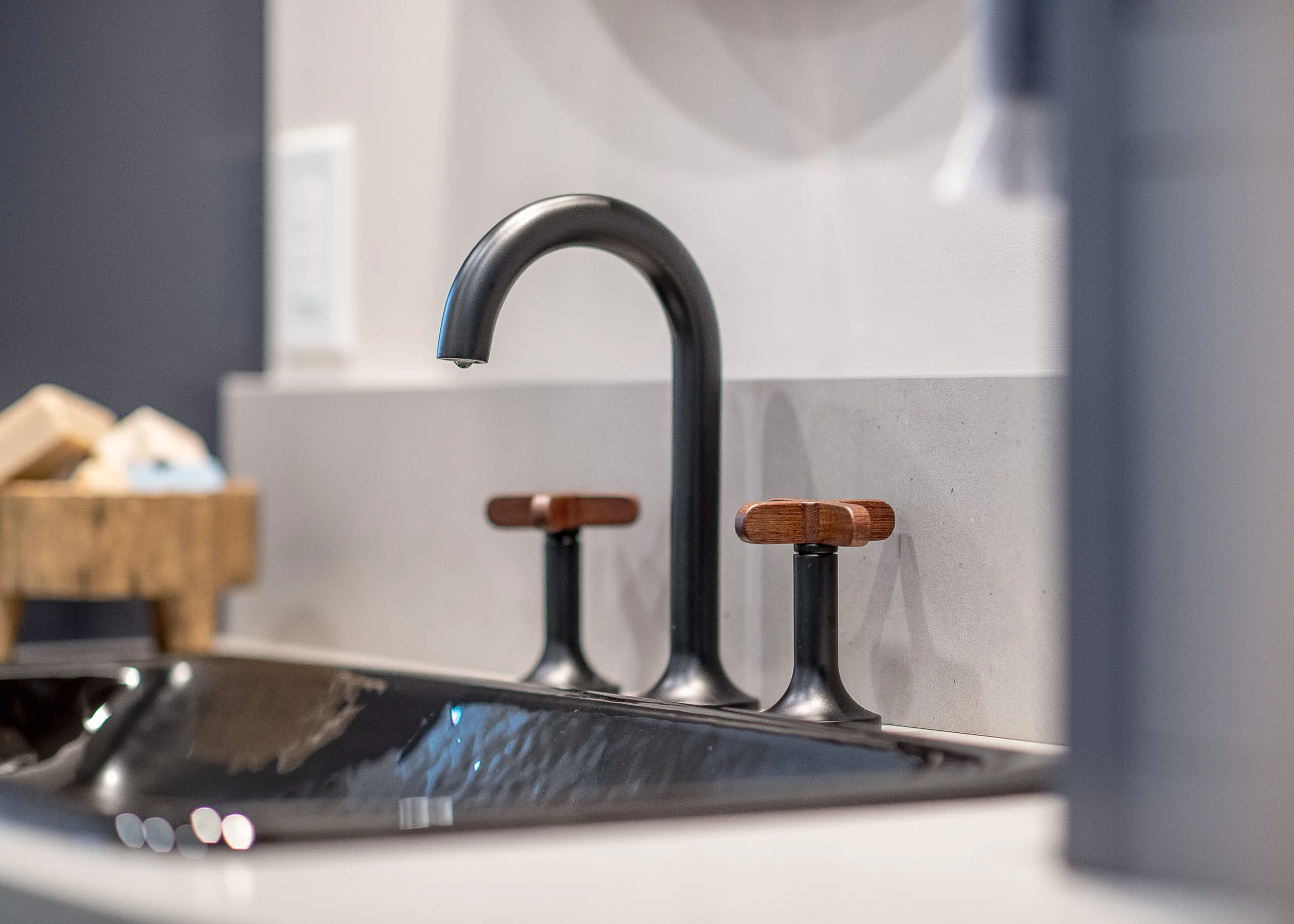 Close up of a black sink and black faucet with wooden handles
