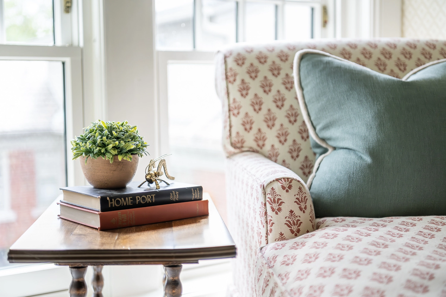 Close up image of a chaise lounge and a wooden side table with books and a succulent on top
