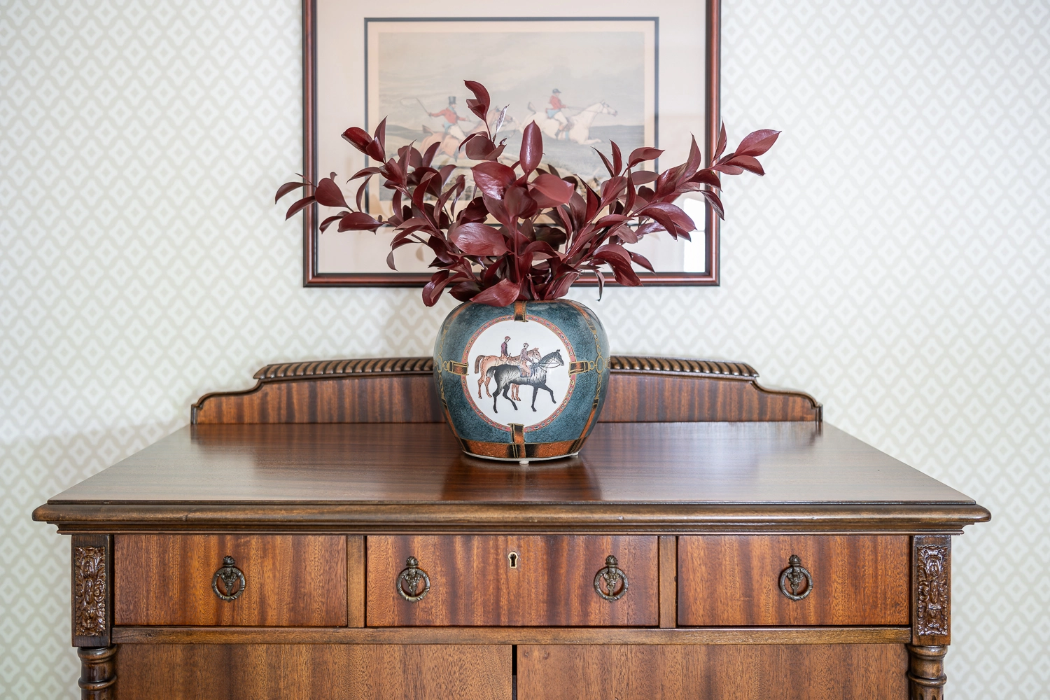 Wooden chest with red florals in a green vase with artwork above