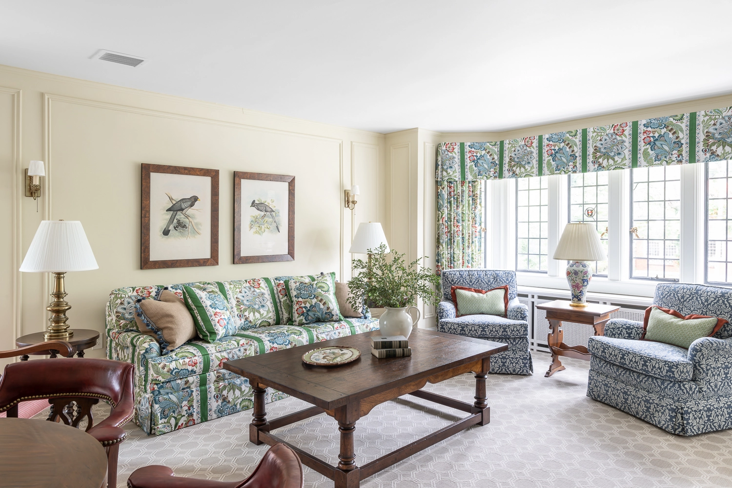 Green patterned sofa with bird artwork above and a walnut coffee table in front