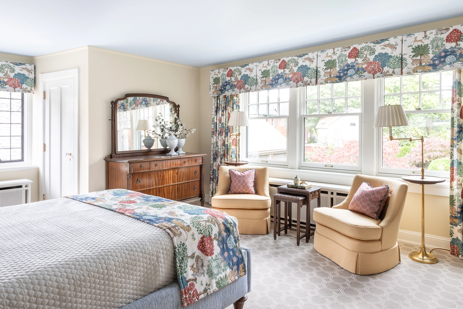 Bedroom with 2 sitting chairs in front of a window and next to a wooden dresser