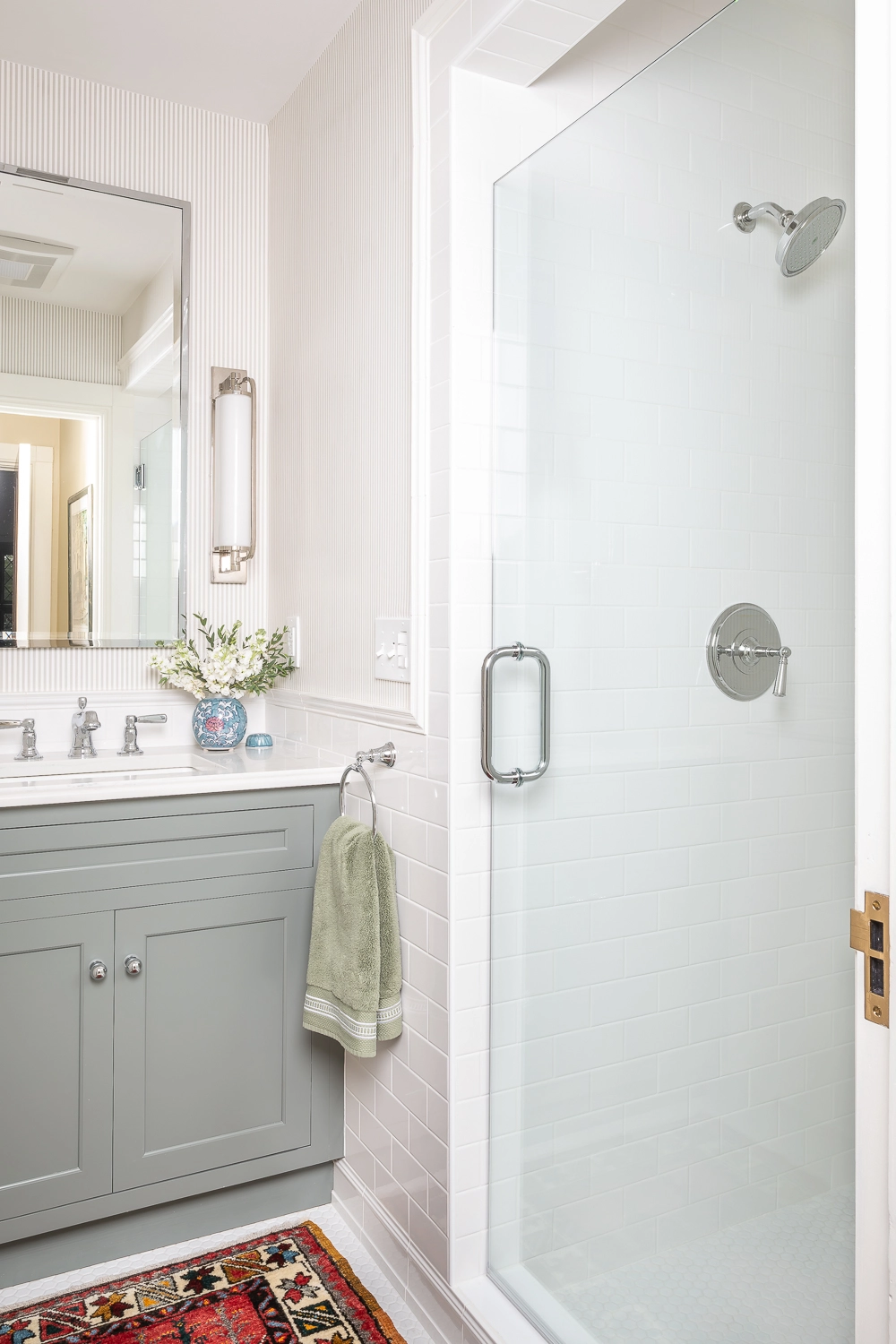 White bathroom with light blue cabinets, looking at the mirror and sink