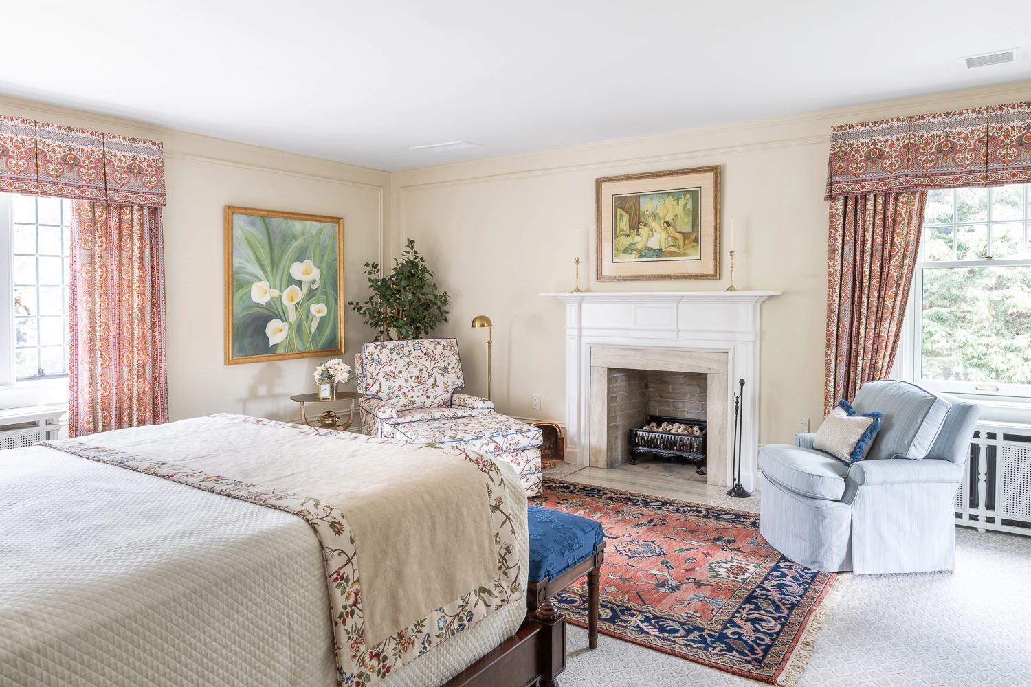 Image in a bedroom looking towards a fireplace with an oriental rug in front artwork above
