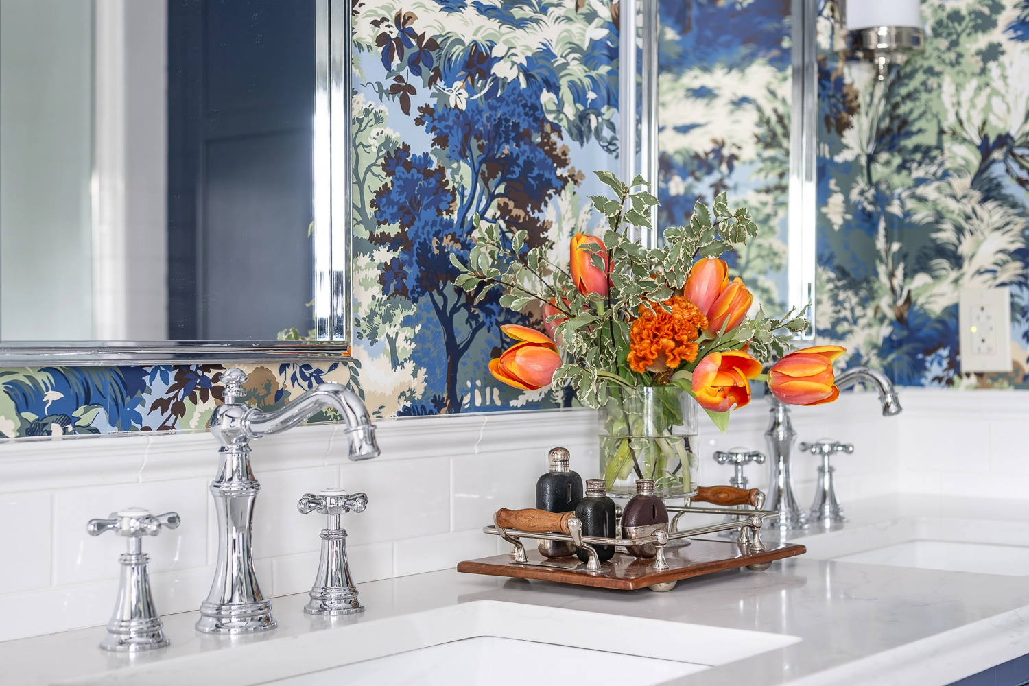 Bathroom vanity image focusing on orange florals on a tray sitting in front of the blue patterned wallpaper