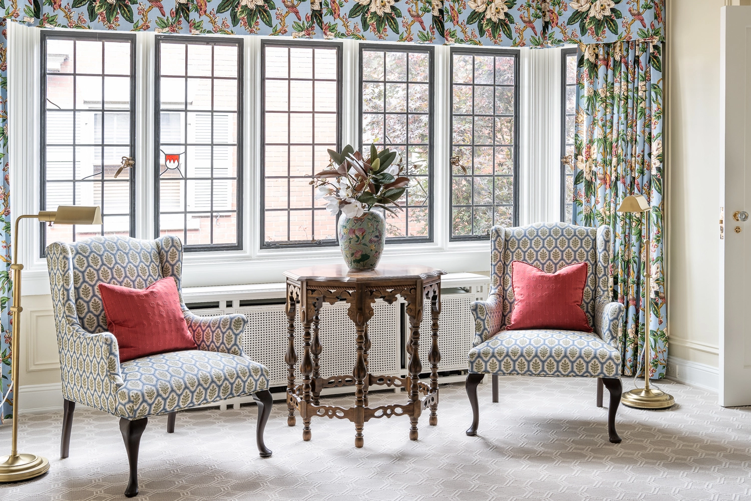 Set of upholstered chairs and table sitting in front of a large window with a valance and side panels