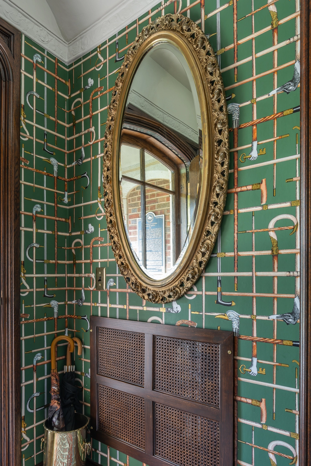 Image looking into vestibule with umbrella stand, mirror, and green wallpaper