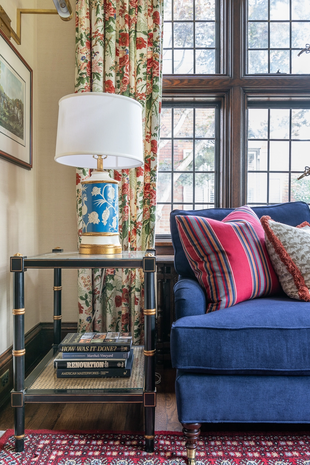 Image in a sitting room looking at a blue sofa and side table with a blue and gold lamp