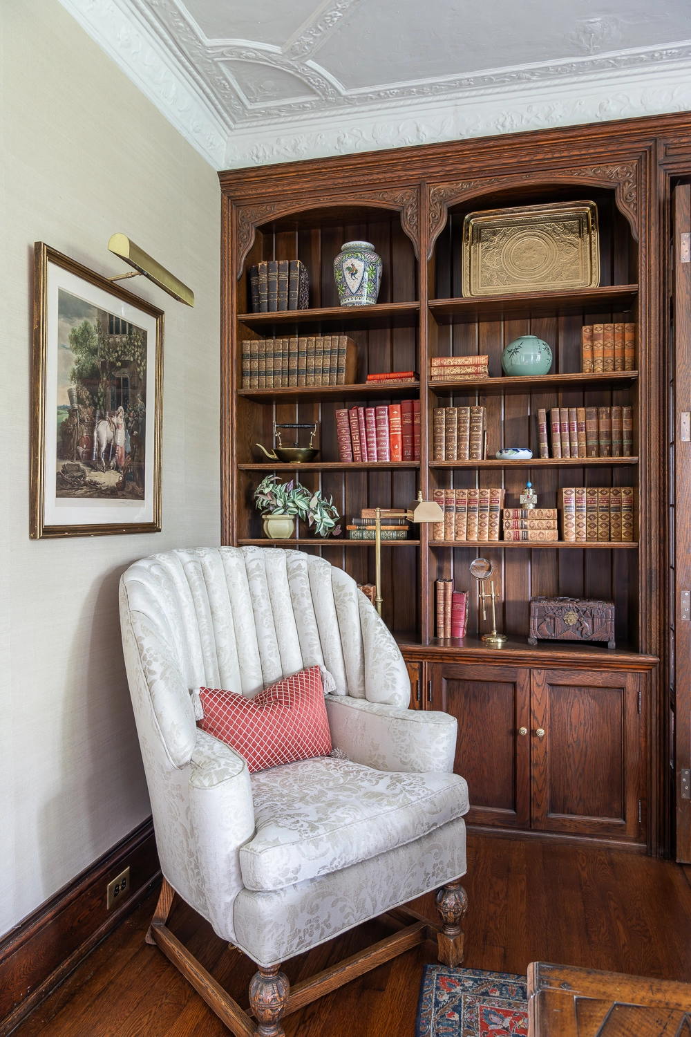 Image looking at a wooden bookcase with an upholstered chair sitting in front