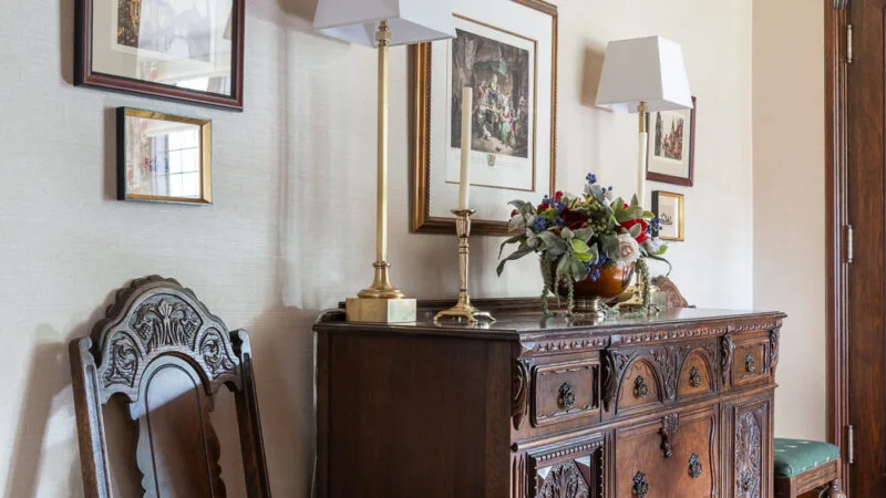 Image of a hallway with a wooden chest beside a chair and artwork above